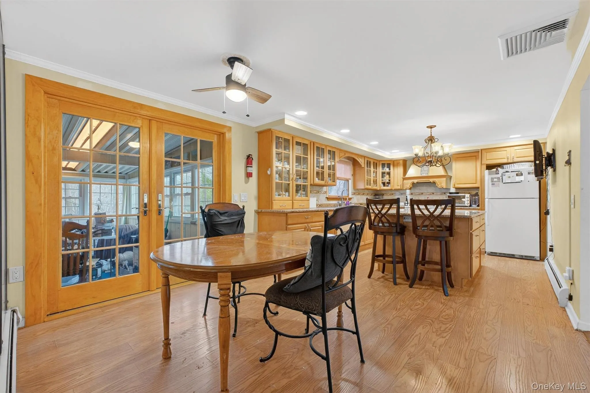 Dining space featuring light wood-type flooring, a chandelier, crown molding, baseboard heating, and recessed lighting Dining space featuring light wood-type flooring, a chandelier, crown molding, baseboard heating, and recessed lighting