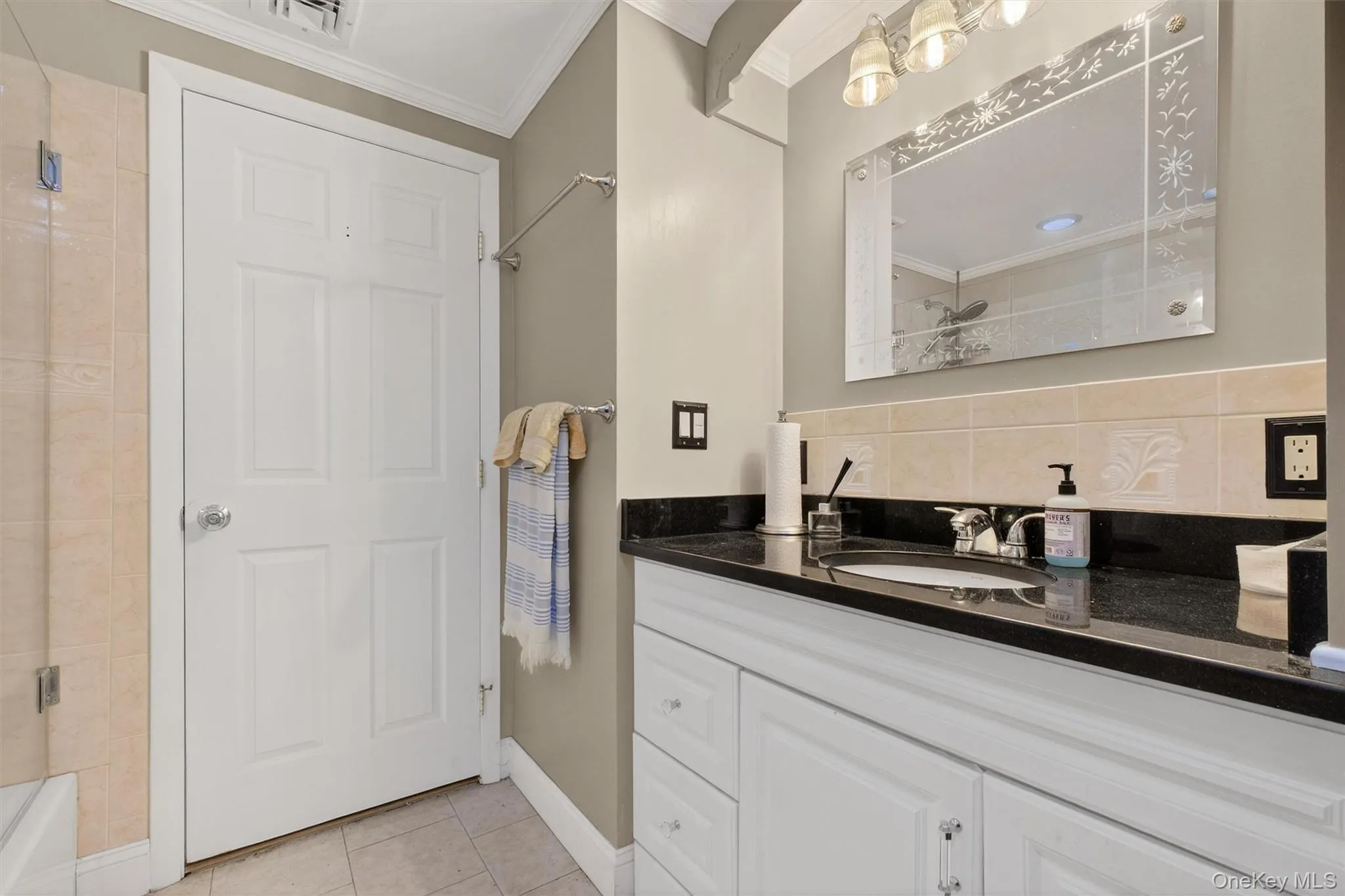 Bathroom with vanity, crown molding, light tile patterned floors, and decorative backsplash Bathroom with vanity, crown molding, light tile patterned floors, and decorative backsplash