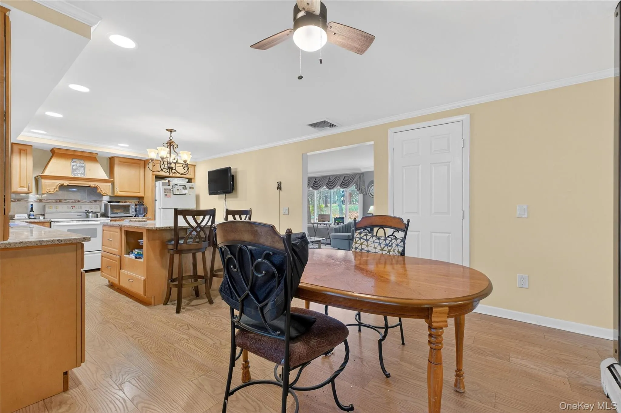 Dining room featuring recessed lighting, a chandelier, crown molding, light wood-style floors, and a ceiling fan Dining room featuring recessed lighting, a chandelier, crown molding, light wood-style floors, and a ceiling fan