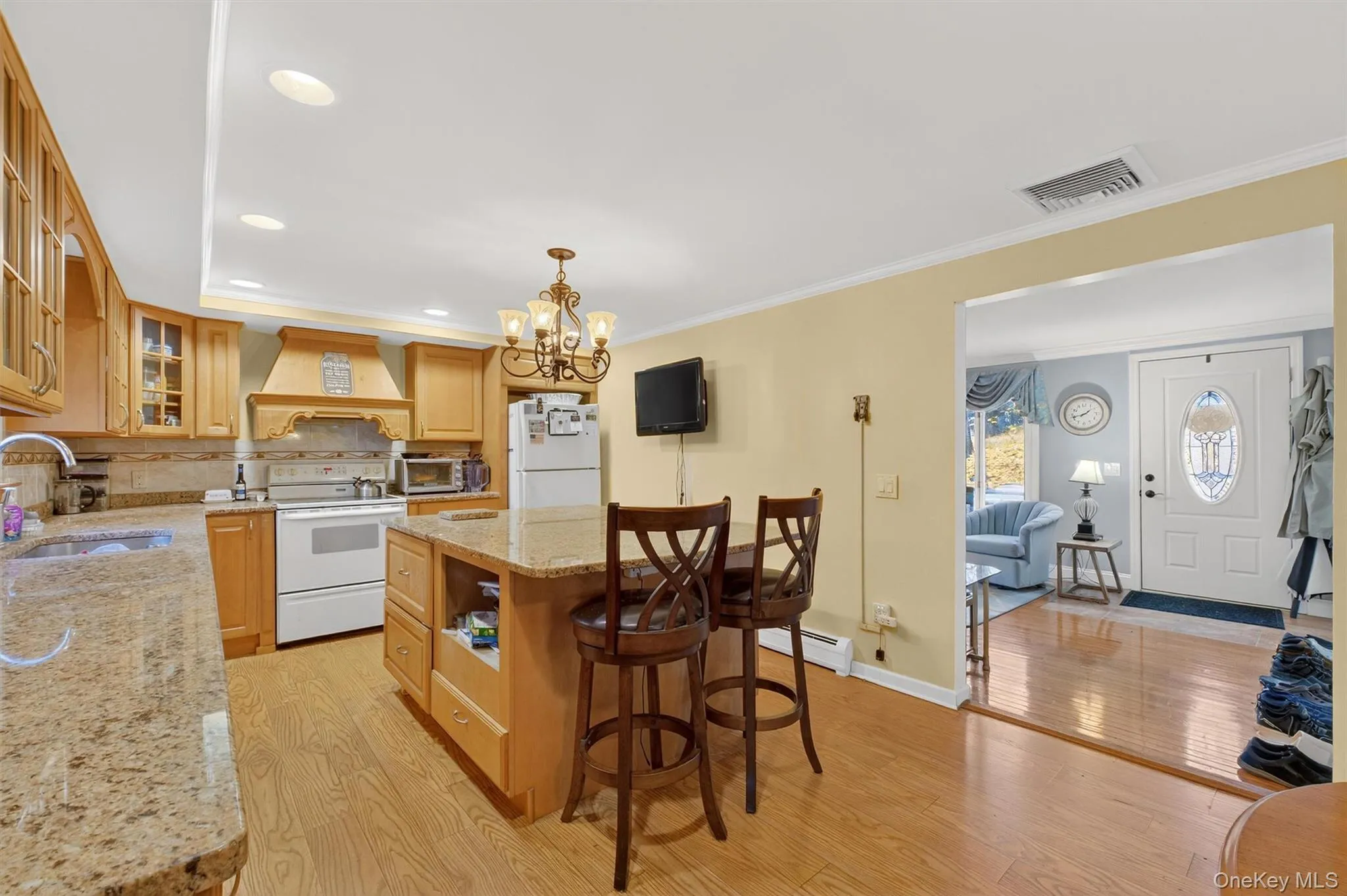 Kitchen with light stone counters, glass insert cabinets, light wood finished floors, white appliances, and a center island Kitchen with light stone counters, glass insert cabinets, light wood finished floors, white appliances, and a center island