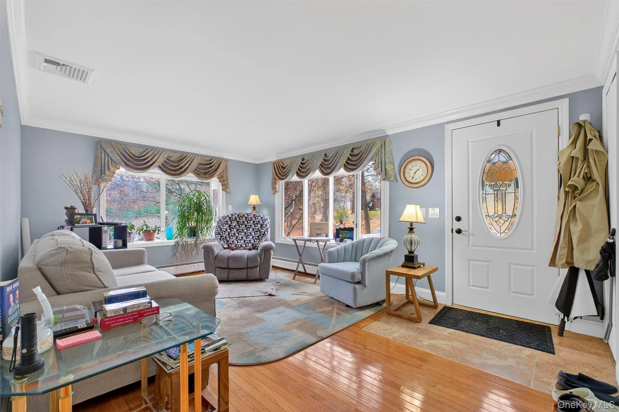 Living area featuring crown molding, wood-type flooring, and a baseboard heating unit Living area featuring crown molding, wood-type flooring, and a baseboard heating unit