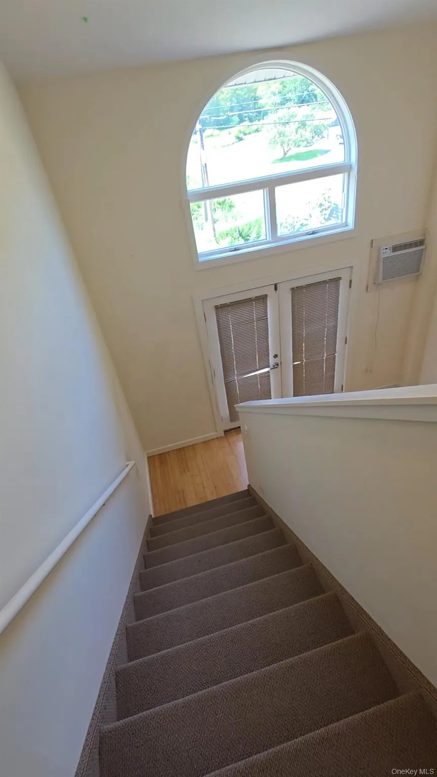 Stairway with wood finished floors, a wall mounted AC, and french doors Stairway with wood finished floors, a wall mounted AC, and french doors