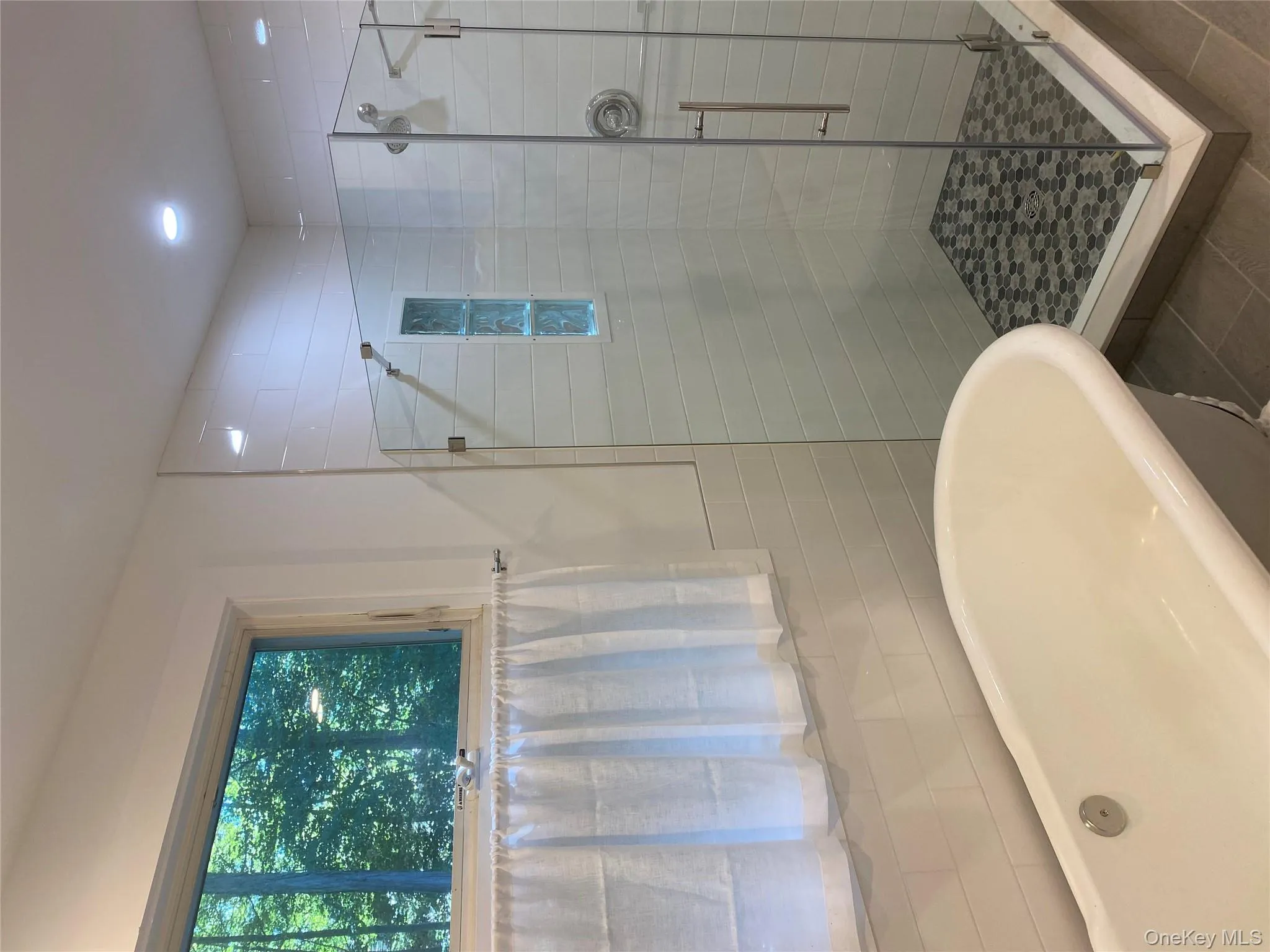 Bathroom featuring a soaking tub, a stall shower, tile patterned flooring, and tile walls Bathroom featuring a soaking tub, a stall shower, tile patterned flooring, and tile walls