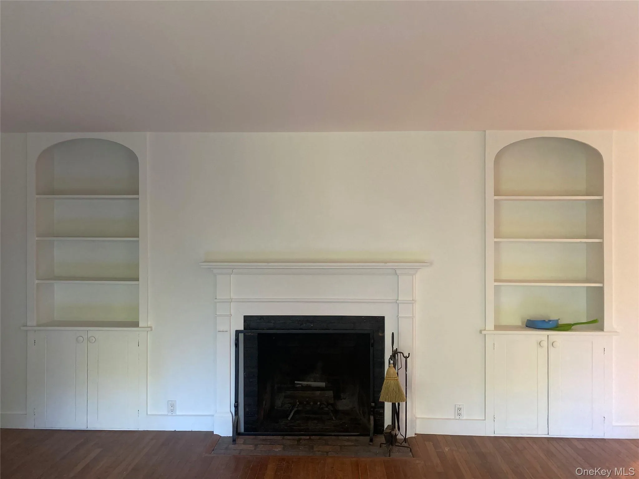 Living area with built in features, dark wood-style flooring, and a fireplace with flush hearth Living area with built in features, dark wood-style flooring, and a fireplace with flush hearth
