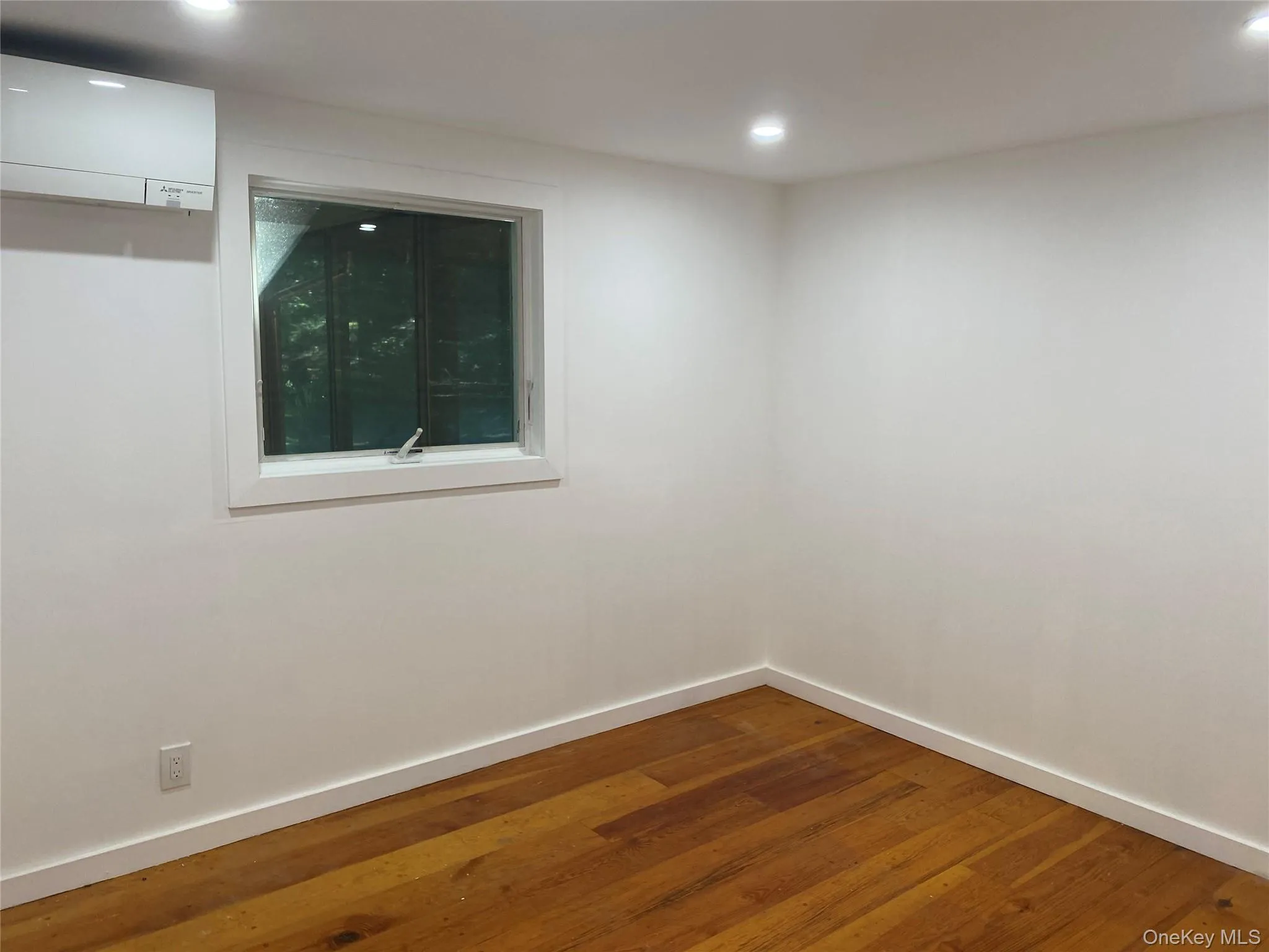 Spare room with dark wood-style floors, a wall mounted AC, and recessed lighting Spare room with dark wood-style floors, a wall mounted AC, and recessed lighting