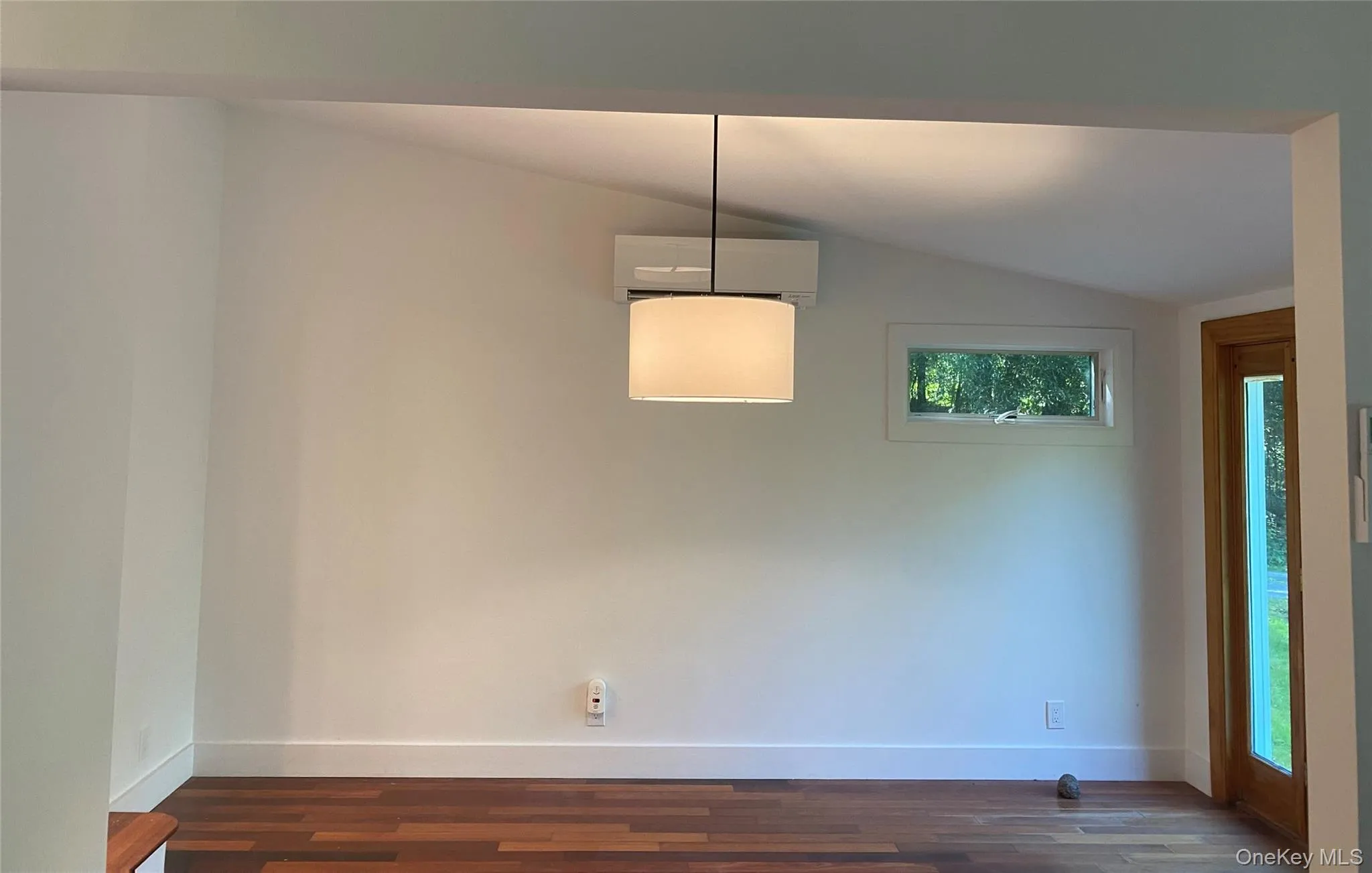 Unfurnished dining area featuring vaulted ceiling, an AC wall unit, and dark wood-type flooring Unfurnished dining area featuring vaulted ceiling, an AC wall unit, and dark wood-type flooring