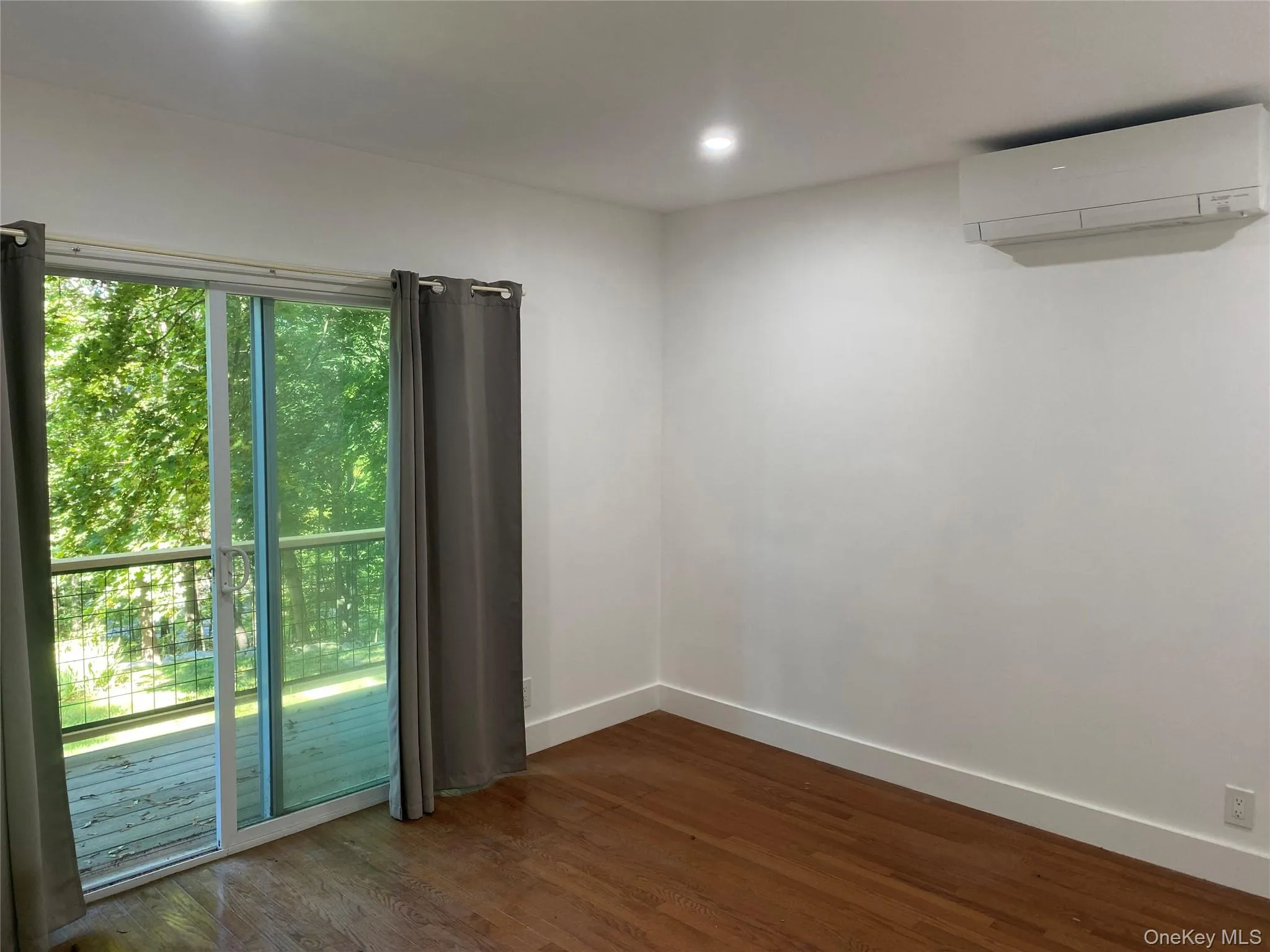 Unfurnished room with dark wood-style floors, a wall mounted AC, and recessed lighting Unfurnished room with dark wood-style floors, a wall mounted AC, and recessed lighting