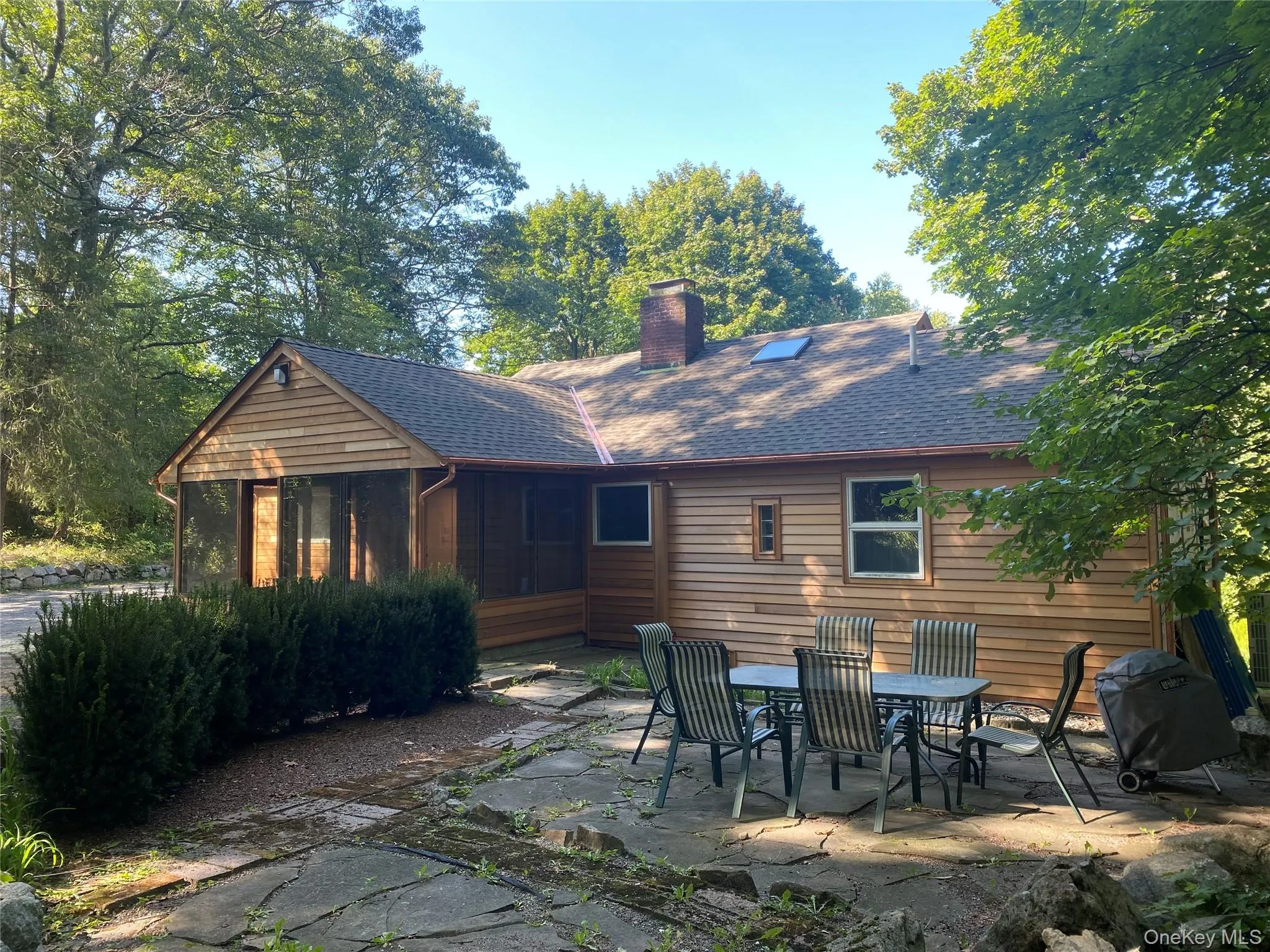Back of house featuring a shingled roof, a patio area, a chimney, and outdoor dining space Back of house featuring a shingled roof, a patio area, a chimney, and outdoor dining space