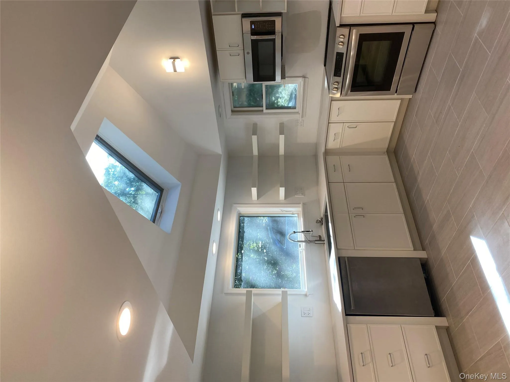 Kitchen featuring open shelves, stainless steel stove, white cabinetry, dishwasher, and vaulted ceiling Kitchen featuring open shelves, stainless steel stove, white cabinetry, dishwasher, and vaulted ceiling