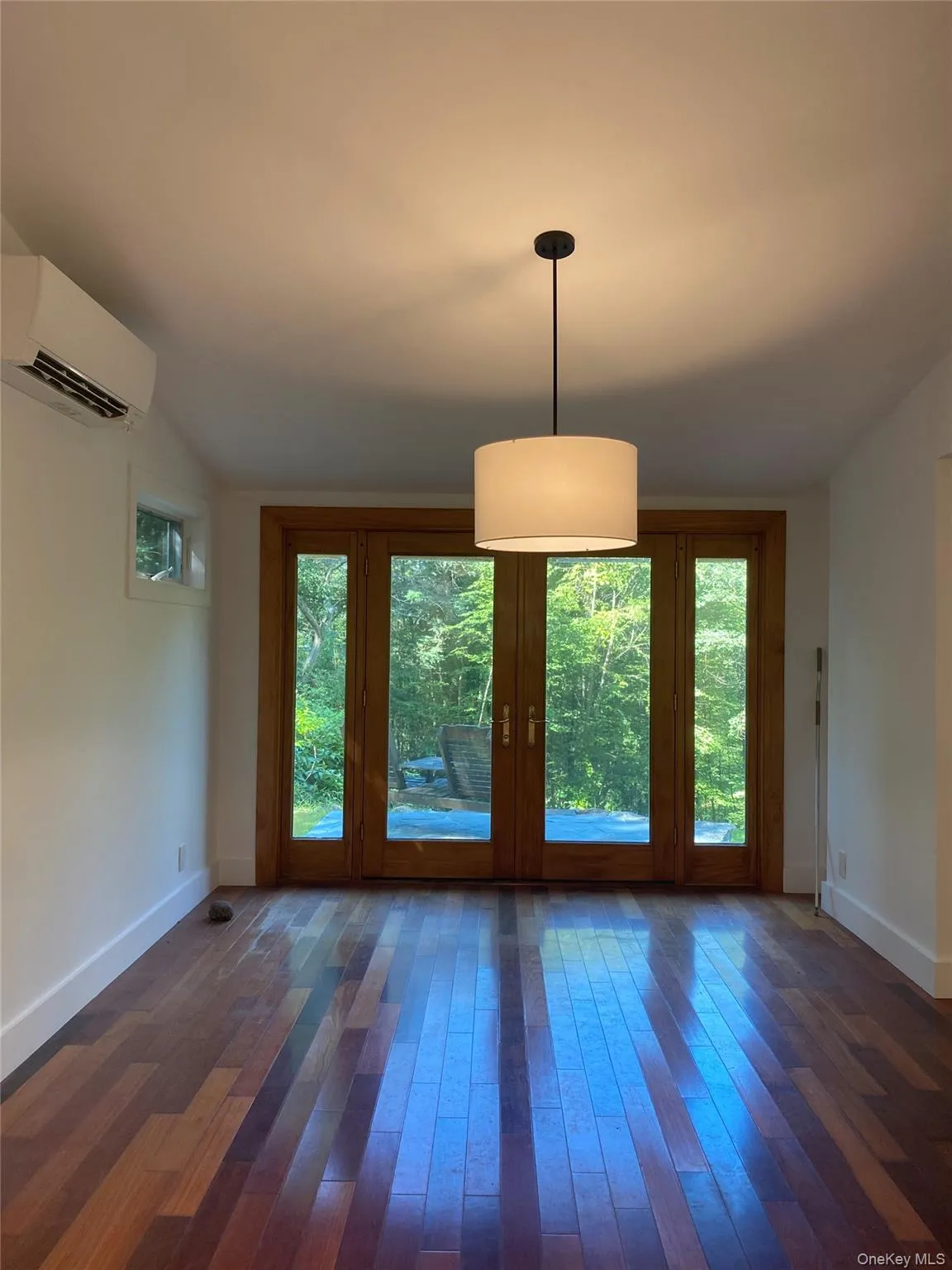 Unfurnished dining area with dark wood-type flooring, a wall mounted air conditioner, and vaulted ceiling Unfurnished dining area with dark wood-type flooring, a wall mounted air conditioner, and vaulted ceiling