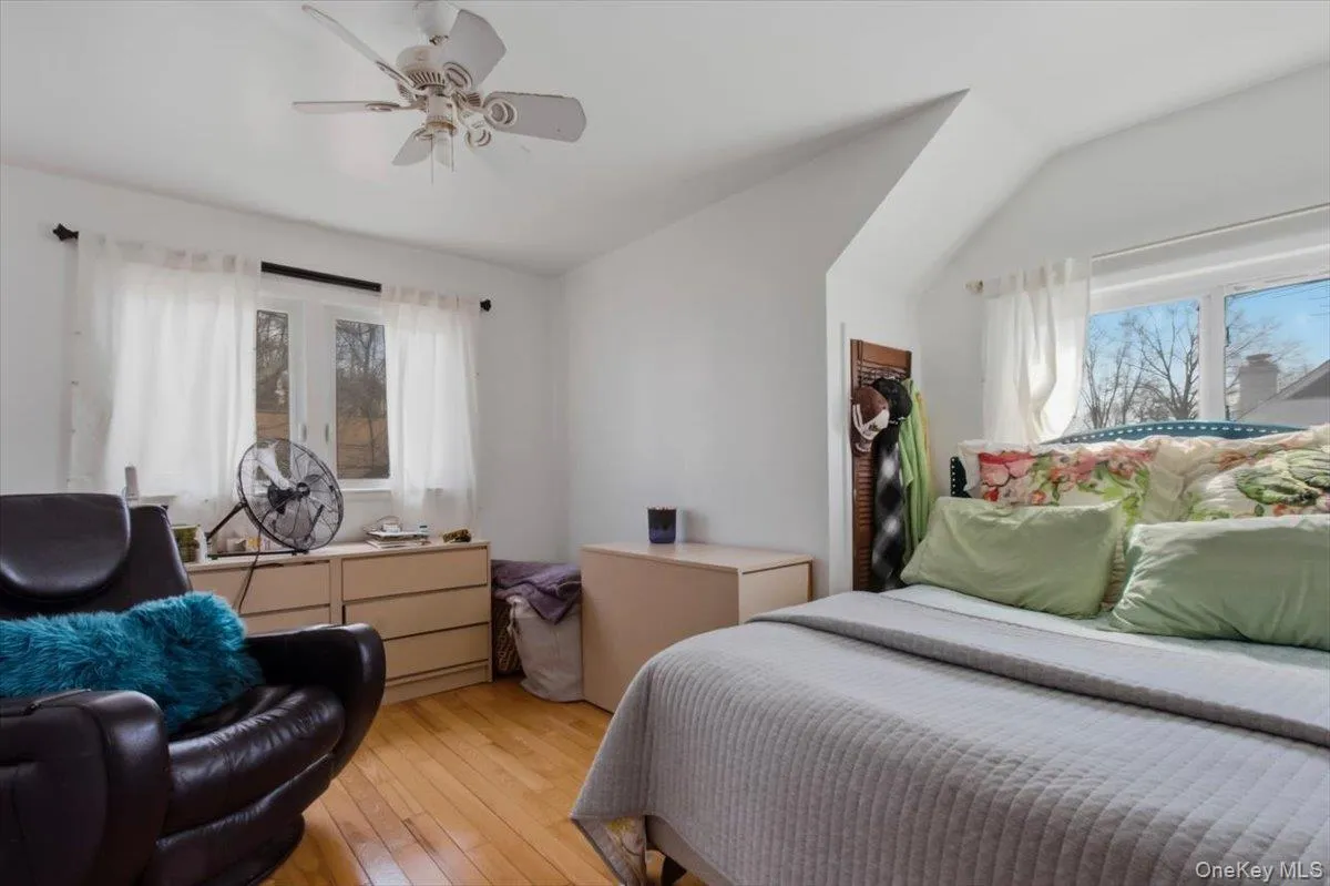 Bedroom featuring light wood-style flooring, a ceiling fan, and a spacious closet Bedroom featuring light wood-style flooring, a ceiling fan, and a spacious closet