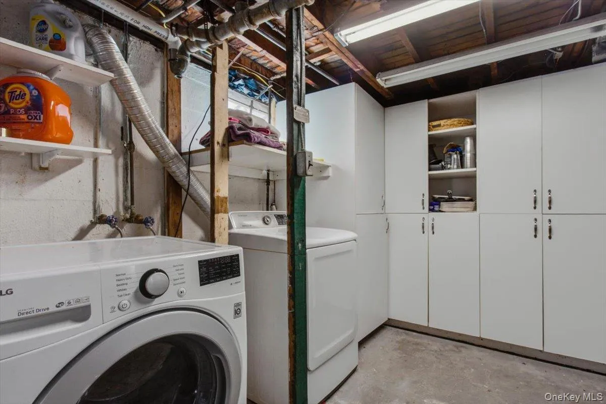 Laundry room featuring concrete flooring, independent washer and dryer, and cabinet space Laundry room featuring concrete flooring, independent washer and dryer, and cabinet space