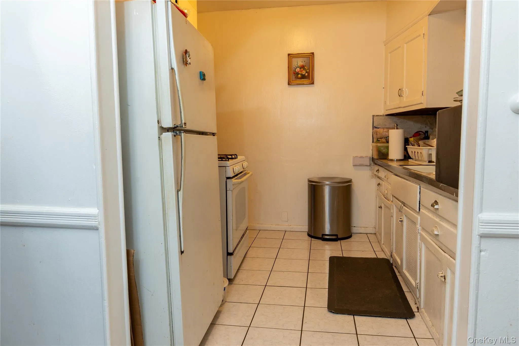 Kitchen with white appliances, white cabinets, light tile patterned floors, and countertops Kitchen with white appliances, white cabinets, light tile patterned floors, and countertops