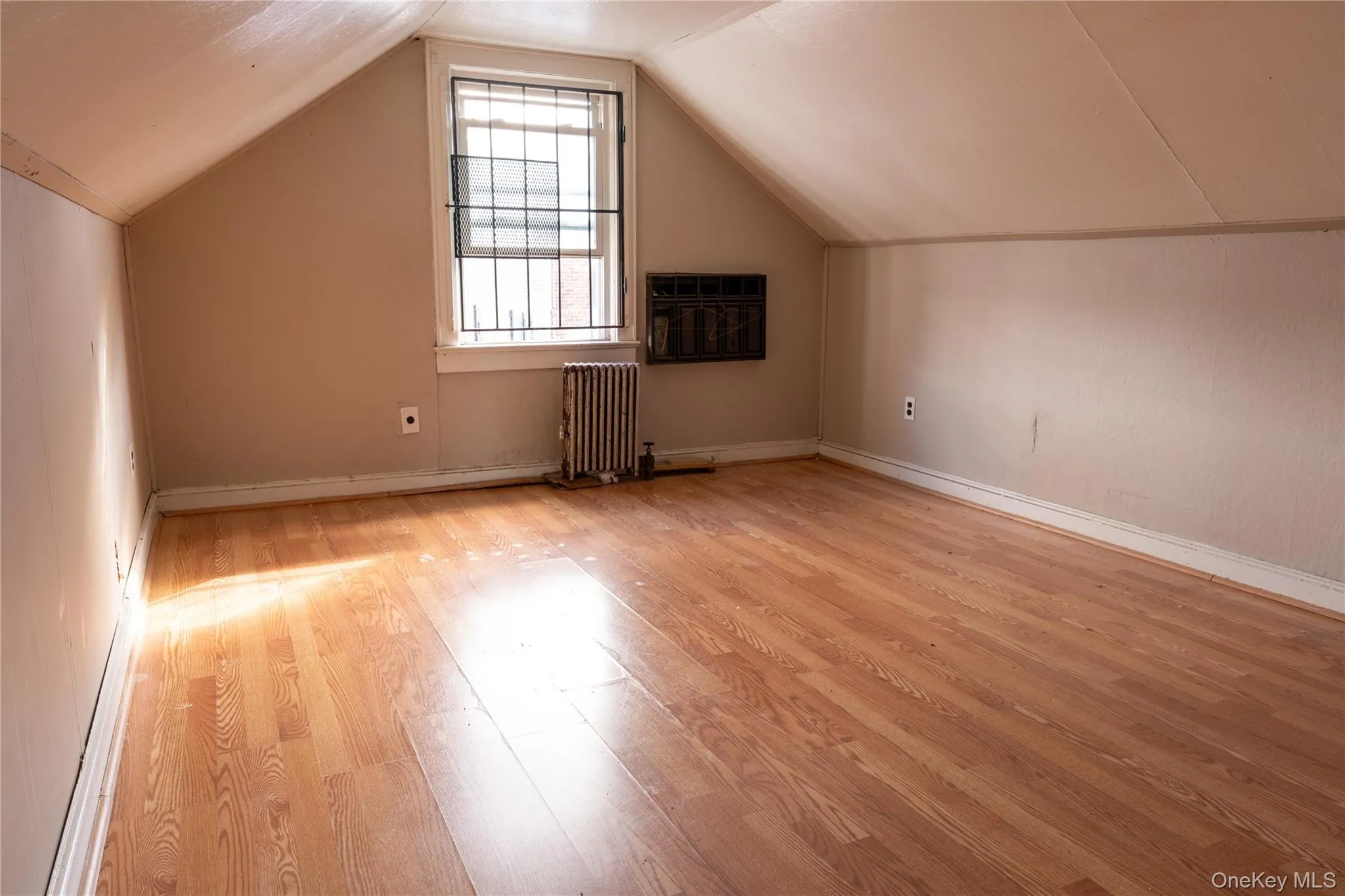 Attic Bonus room featuring radiator and light wood finished floors Attic Bonus room featuring radiator and light wood finished floors