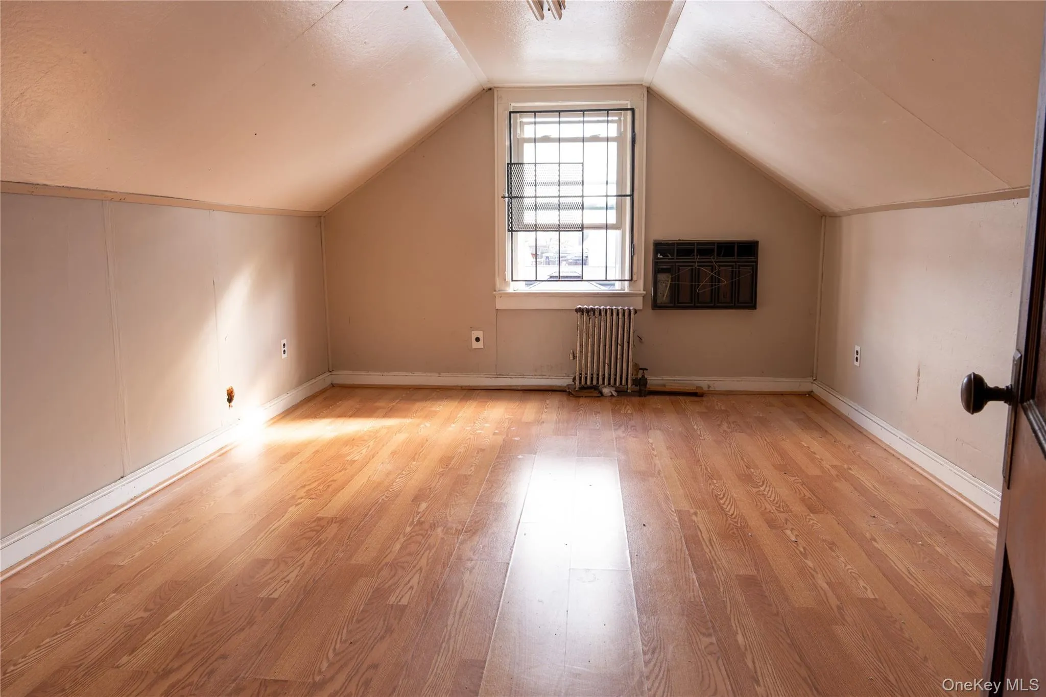 Attic Bonus room with radiator heating unit, light wood-type flooring, and a textured ceiling Attic Bonus room with radiator heating unit, light wood-type flooring, and a textured ceiling
