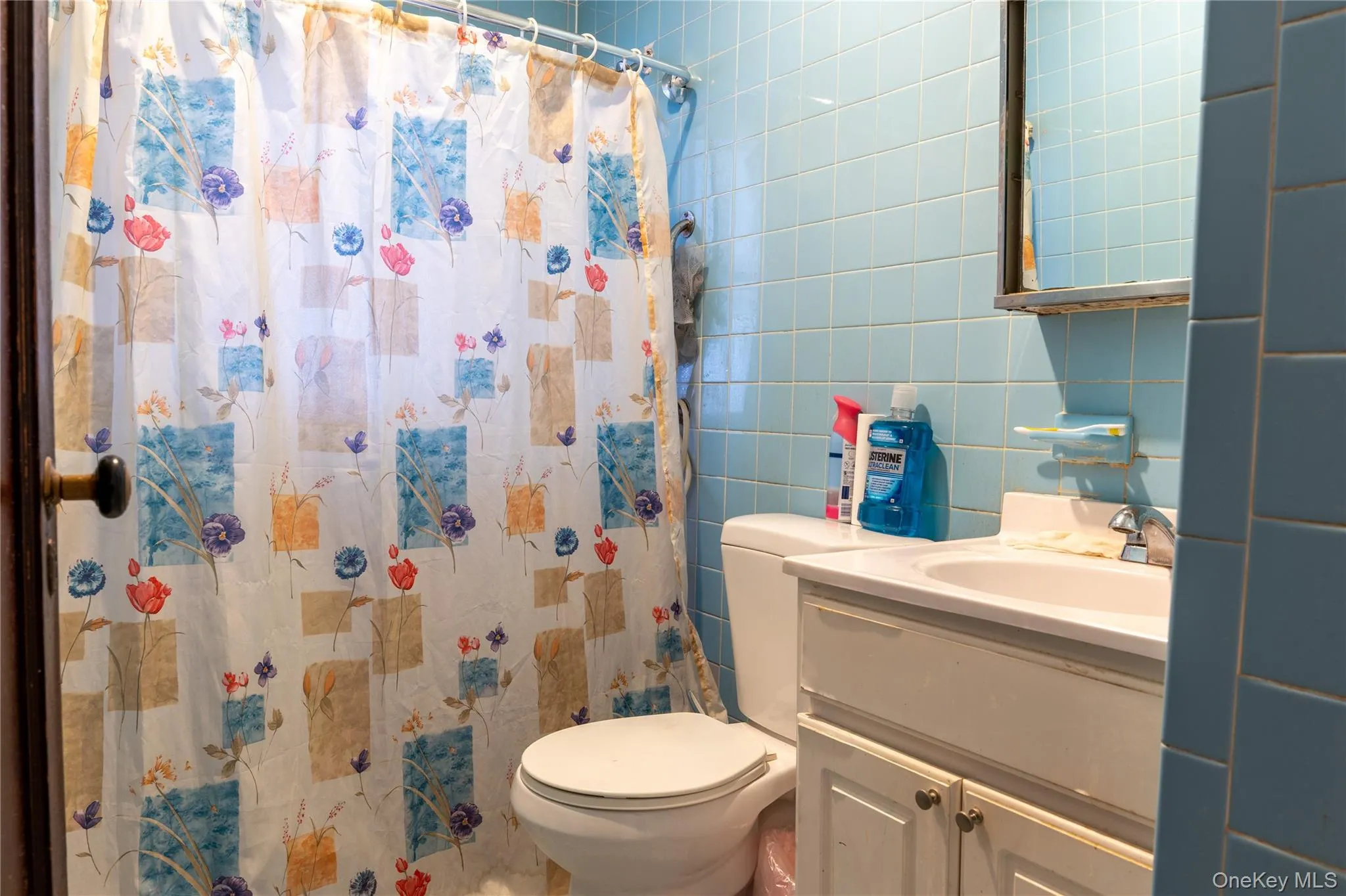 Full bath with tile walls, vanity, and a shower with curtain Full bath with tile walls, vanity, and a shower with curtain
