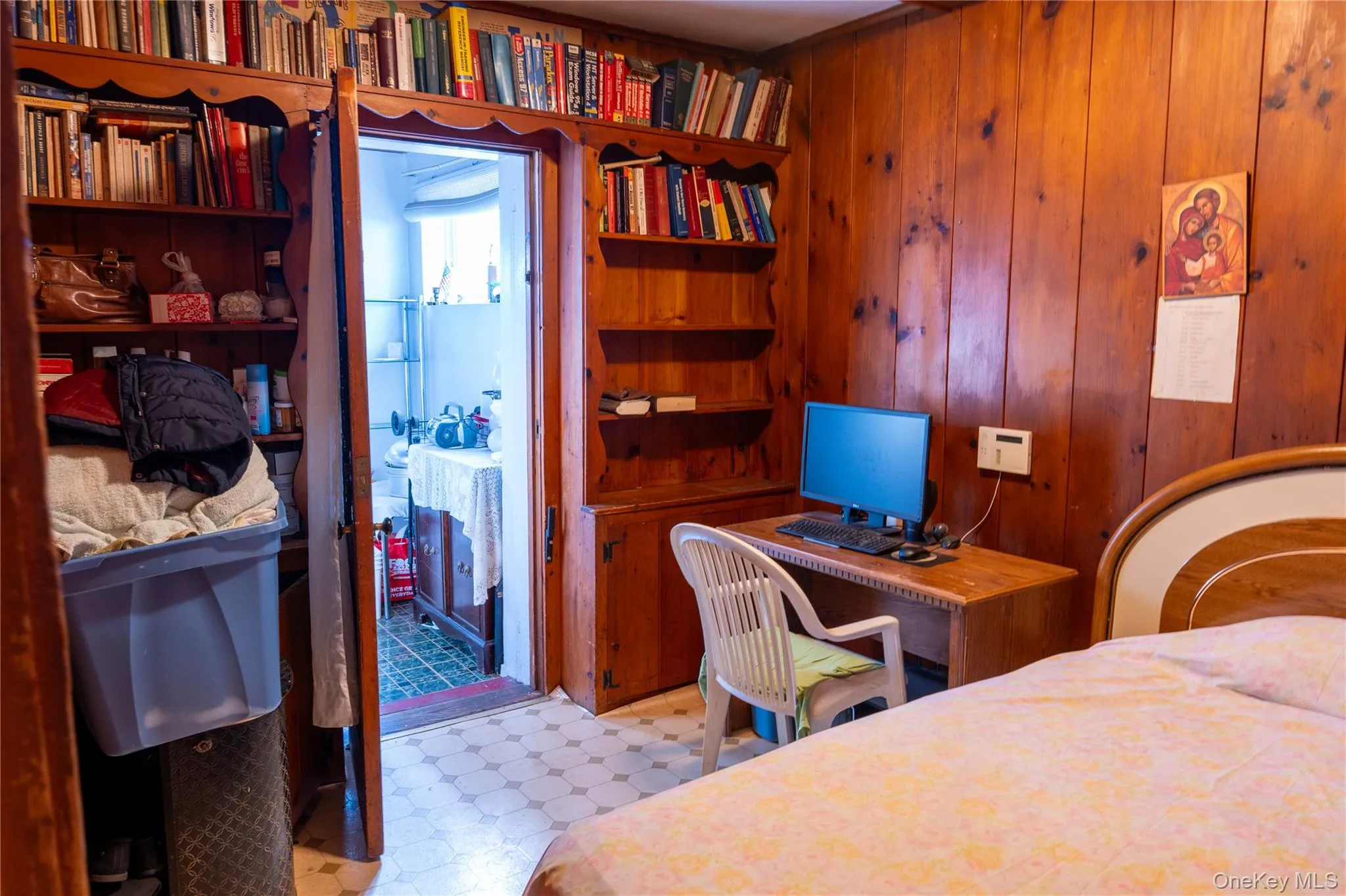 Bedroom featuring light floors, an office area, and wooden walls Bedroom featuring light floors, an office area, and wooden walls