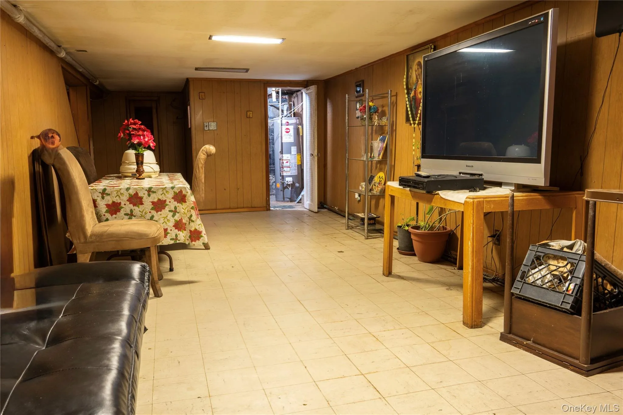 Living room featuring light floors, wooden walls, and gas water heater Living room featuring light floors, wooden walls, and gas water heater