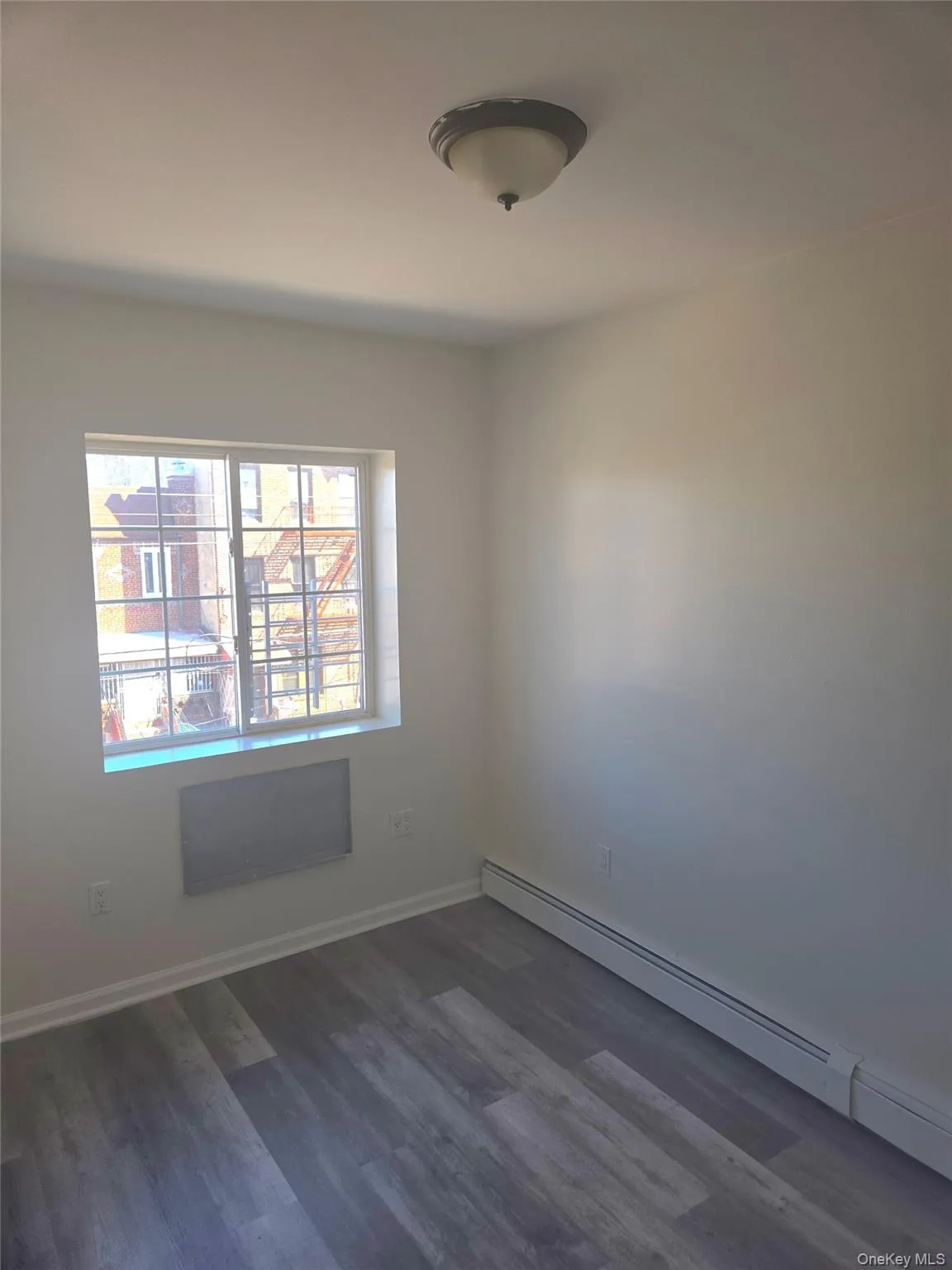 Spare room featuring a baseboard heating unit and dark wood-type flooring Spare room featuring a baseboard heating unit and dark wood-type flooring