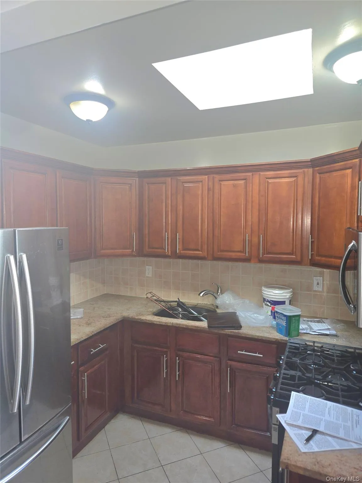 Kitchen with stainless steel appliances, tasteful backsplash, light tile patterned floors, and a skylight Kitchen with stainless steel appliances, tasteful backsplash, light tile patterned floors, and a skylight