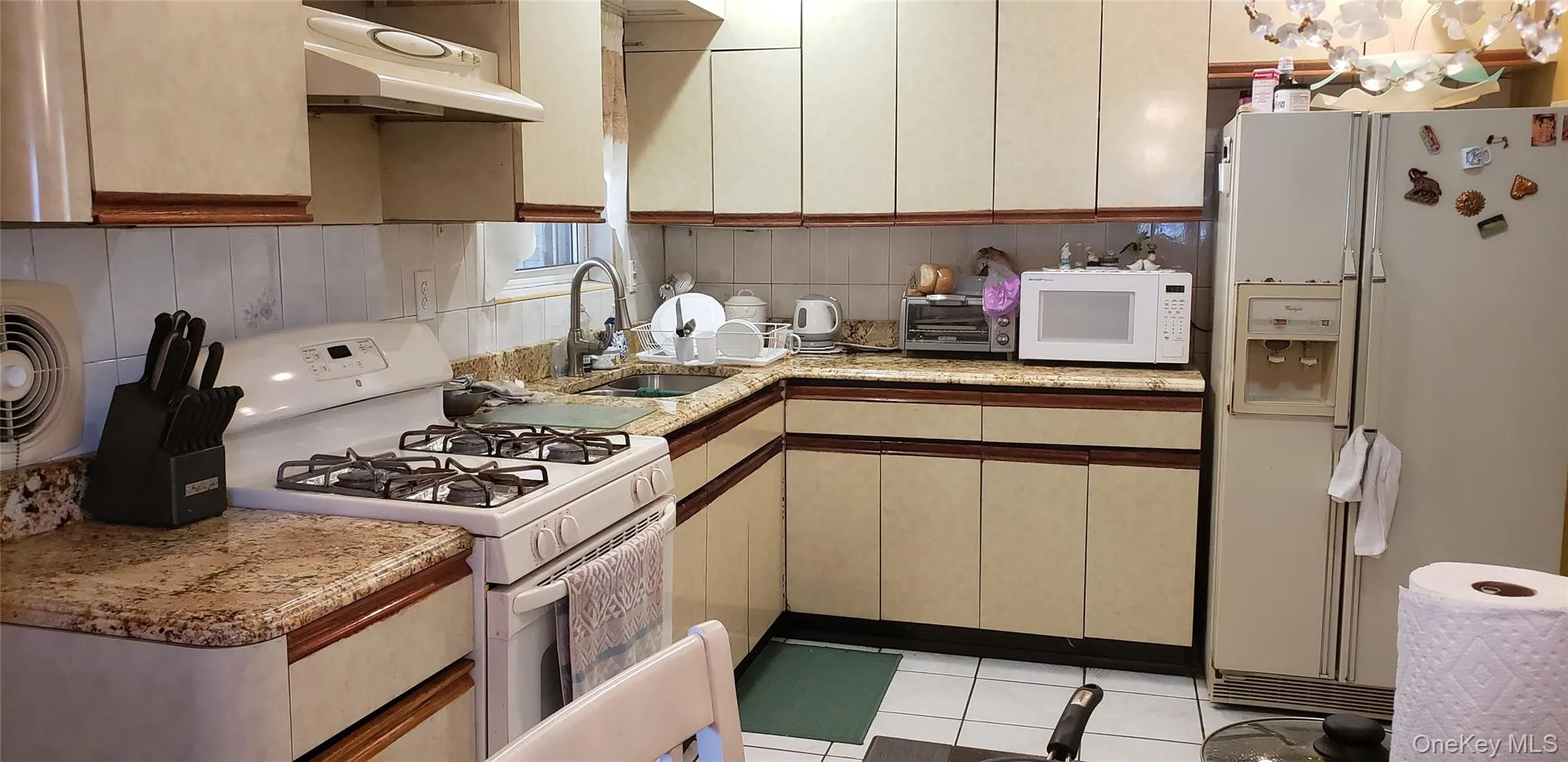 Kitchen with white appliances, exhaust hood, light stone counters, and light tile patterned flooring Kitchen with white appliances, exhaust hood, light stone counters, and light tile patterned flooring