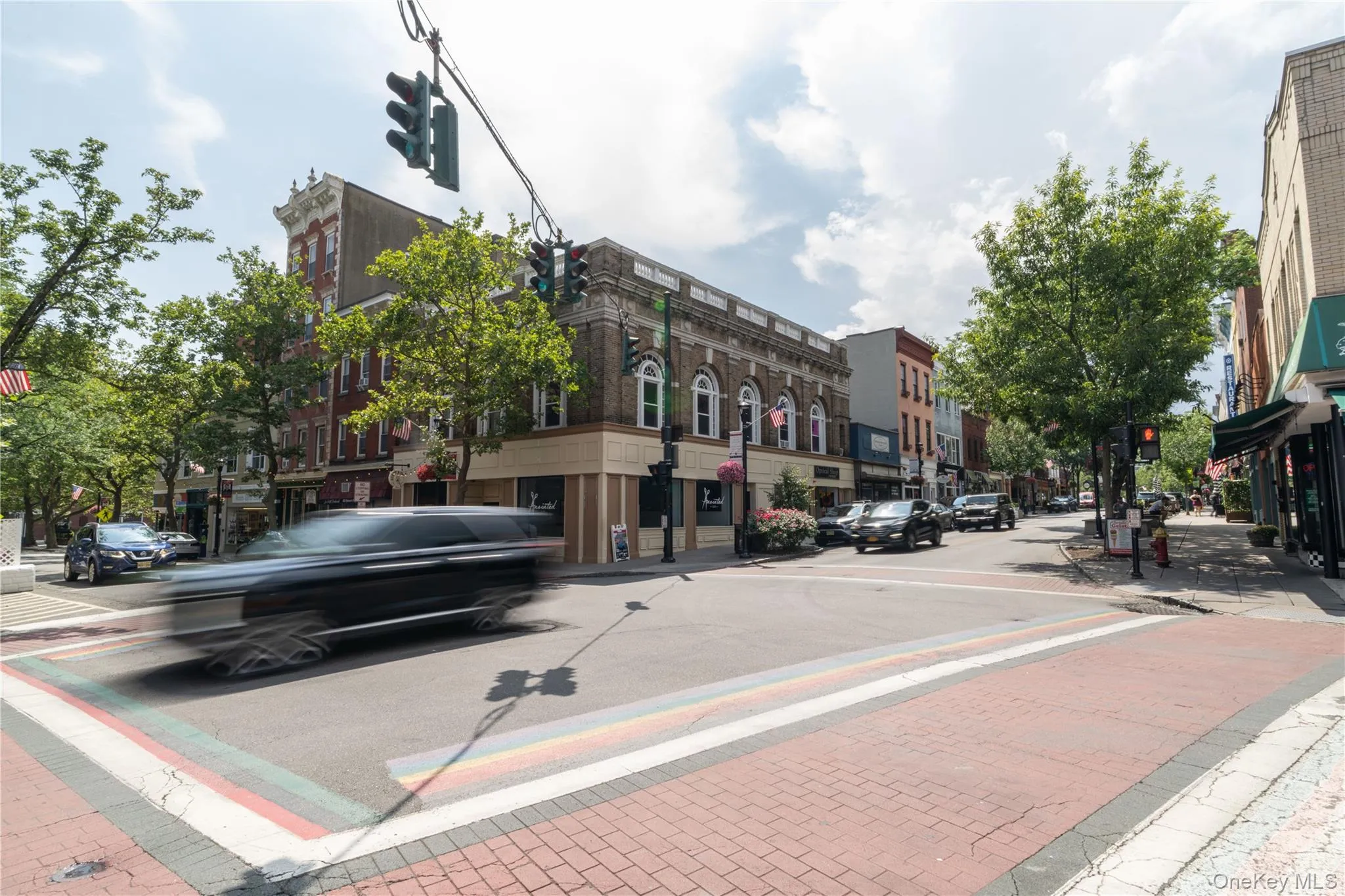 View of asphalt road featuring sidewalks, traffic lights, street lights, and curbs View of asphalt road featuring sidewalks, traffic lights, street lights, and curbs