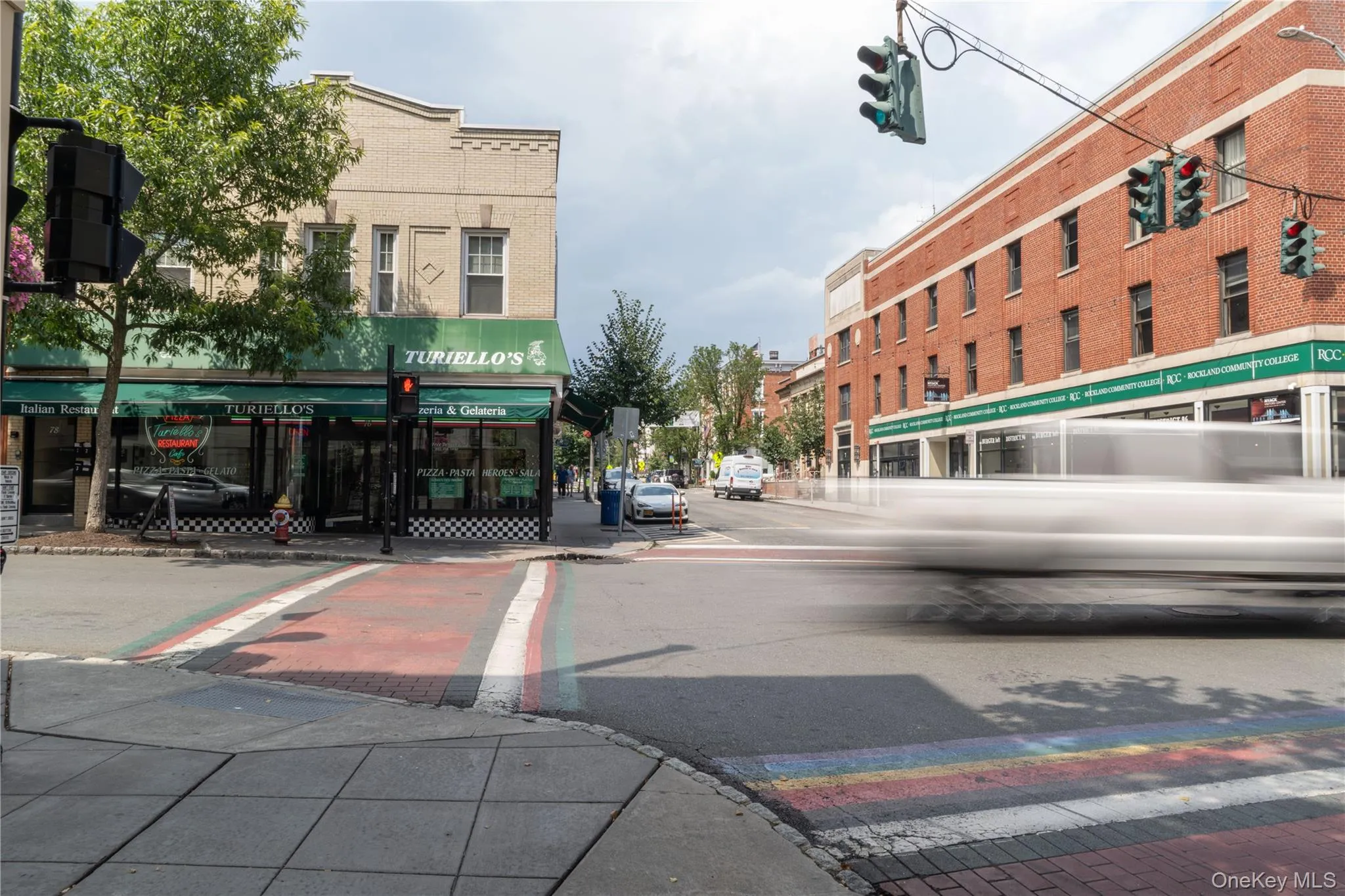 View of asphalt street with traffic lights, sidewalks, street lights, and curbs View of asphalt street with traffic lights, sidewalks, street lights, and curbs