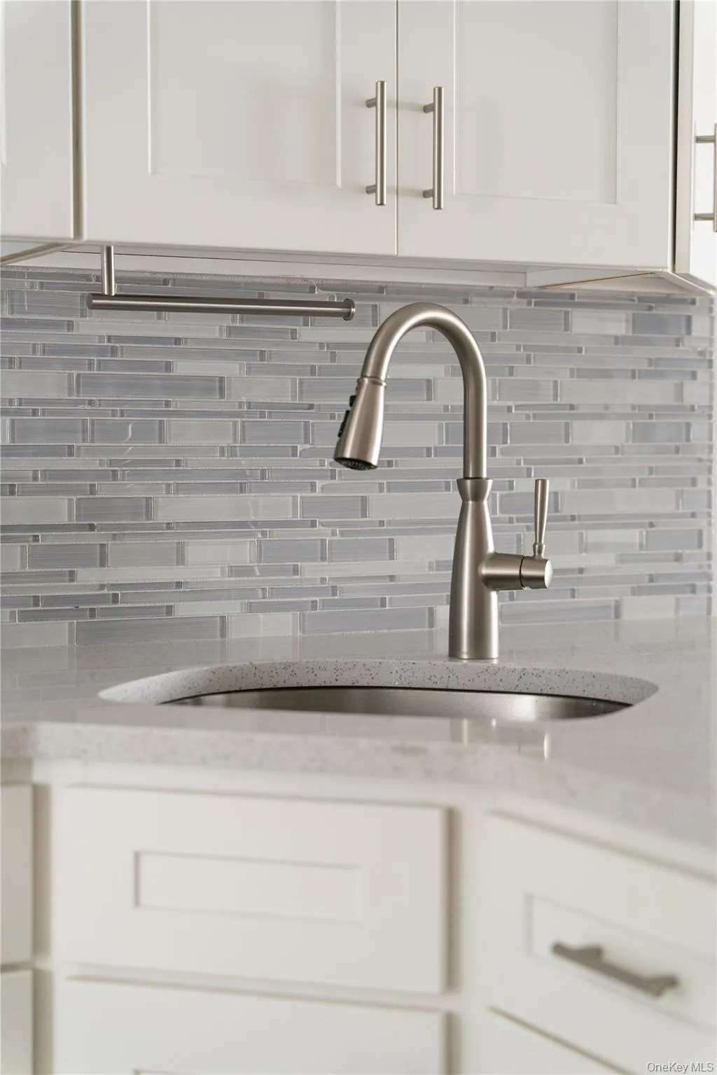 Kitchen view of backsplash, white cabinets, and light stone counters Kitchen view of backsplash, white cabinets, and light stone counters