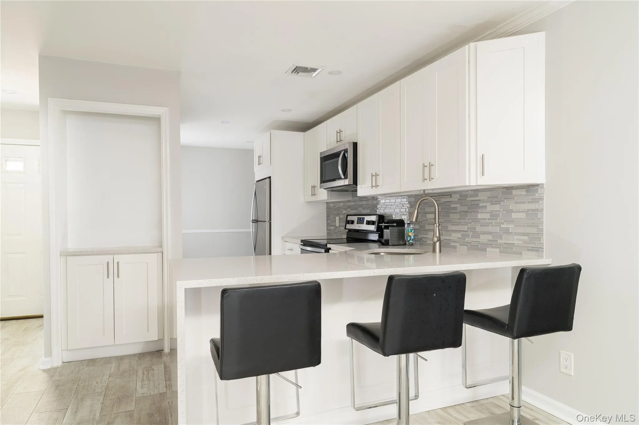 Kitchen with decorative backsplash, a peninsula, light countertops, appliances with stainless steel finishes, and a breakfast bar Kitchen with decorative backsplash, a peninsula, light countertops, appliances with stainless steel finishes, and a breakfast bar