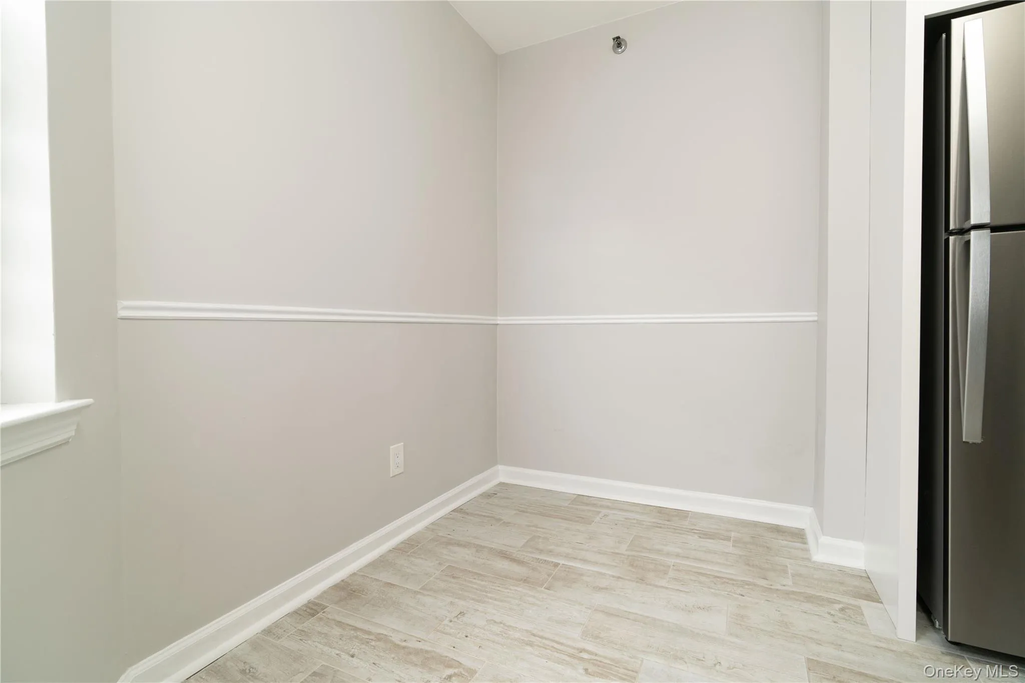 Unfurnished room with baseboards and light wood-style floors Unfurnished room with baseboards and light wood-style floors