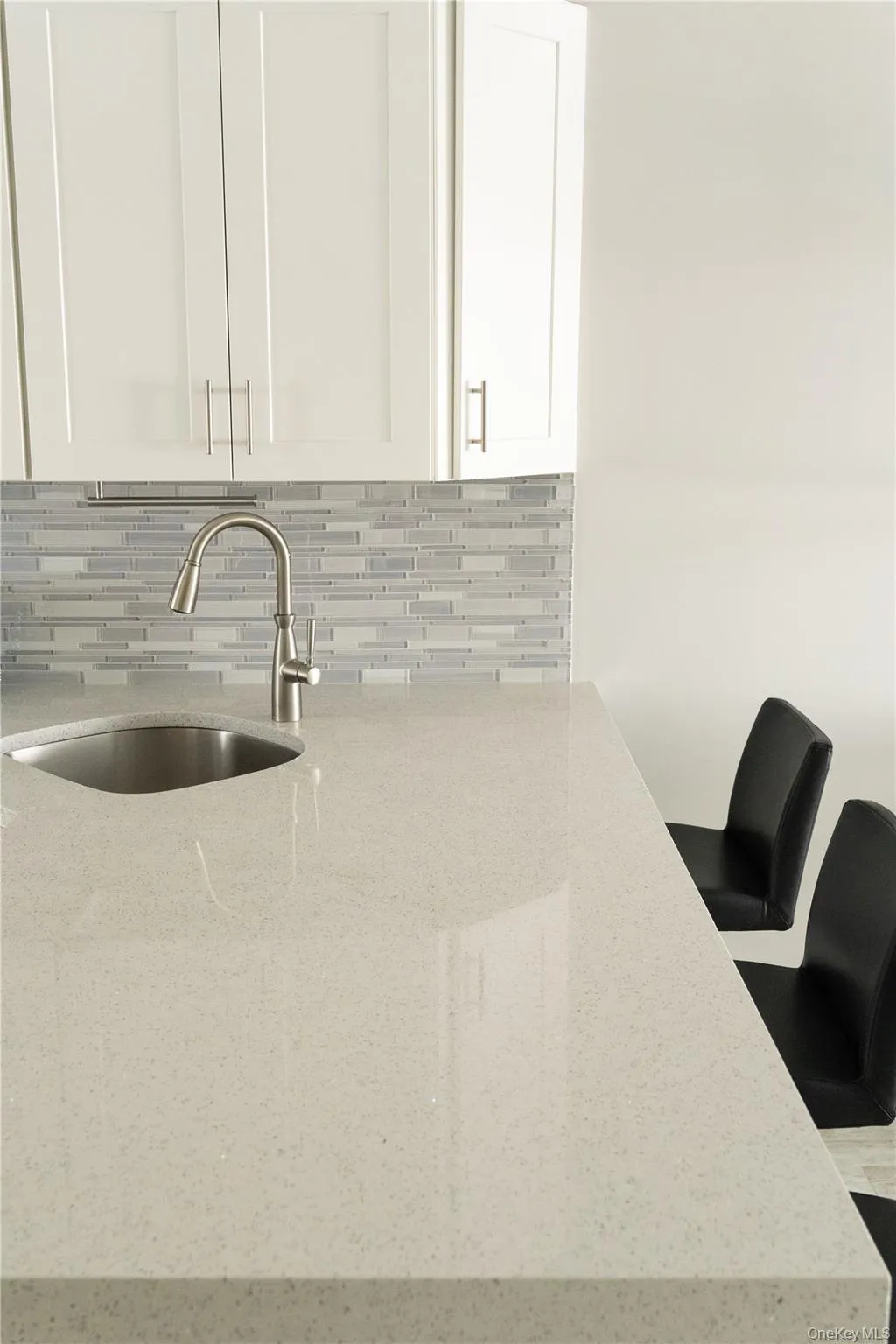 Kitchen view of white cabinets, light stone countertops, and backsplash Kitchen view of white cabinets, light stone countertops, and backsplash