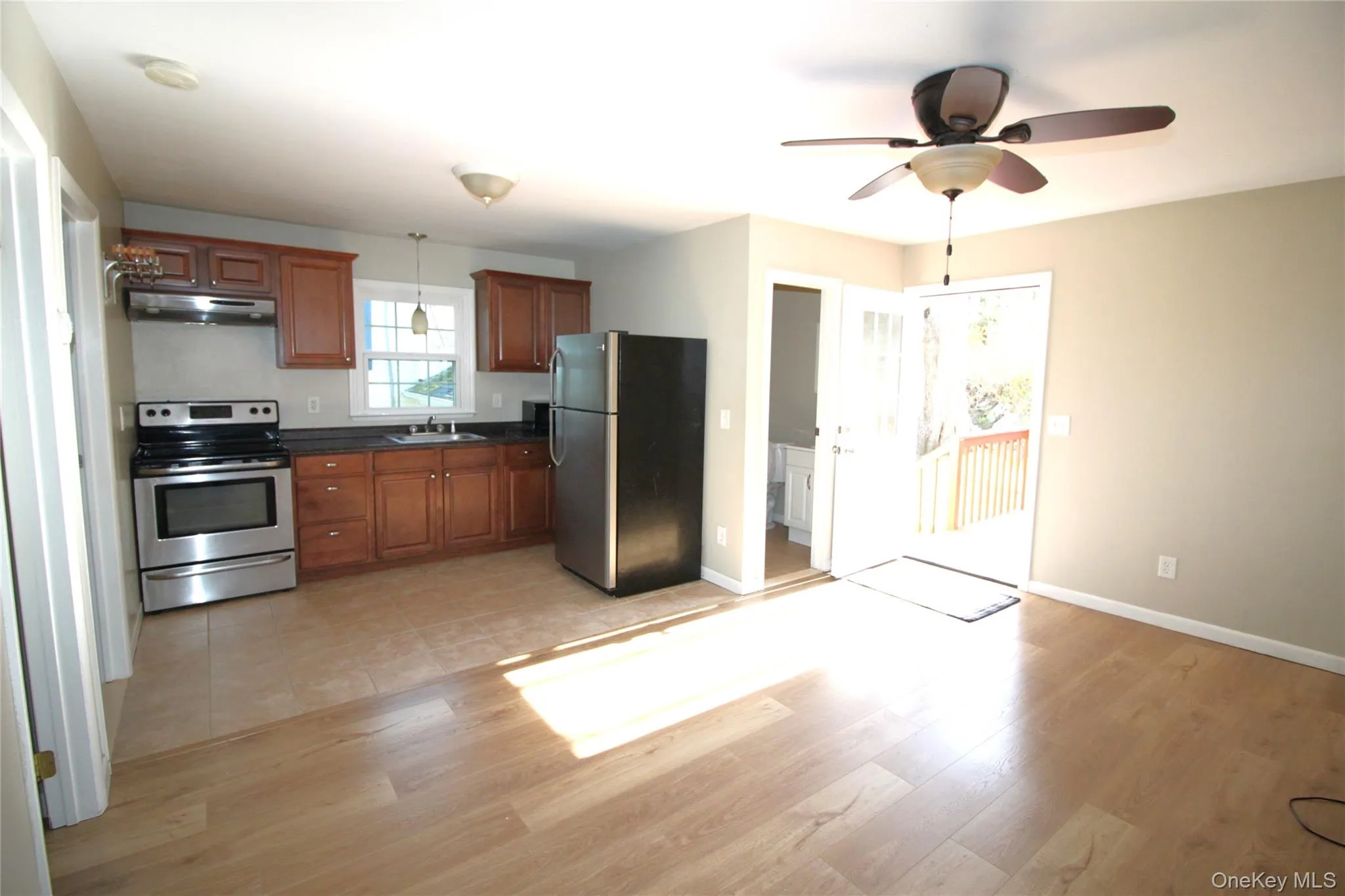 Kitchen featuring dark countertops, appliances with stainless steel finishes, a sink, and light wood-style floors Kitchen featuring dark countertops, appliances with stainless steel finishes, a sink, and light wood-style floors