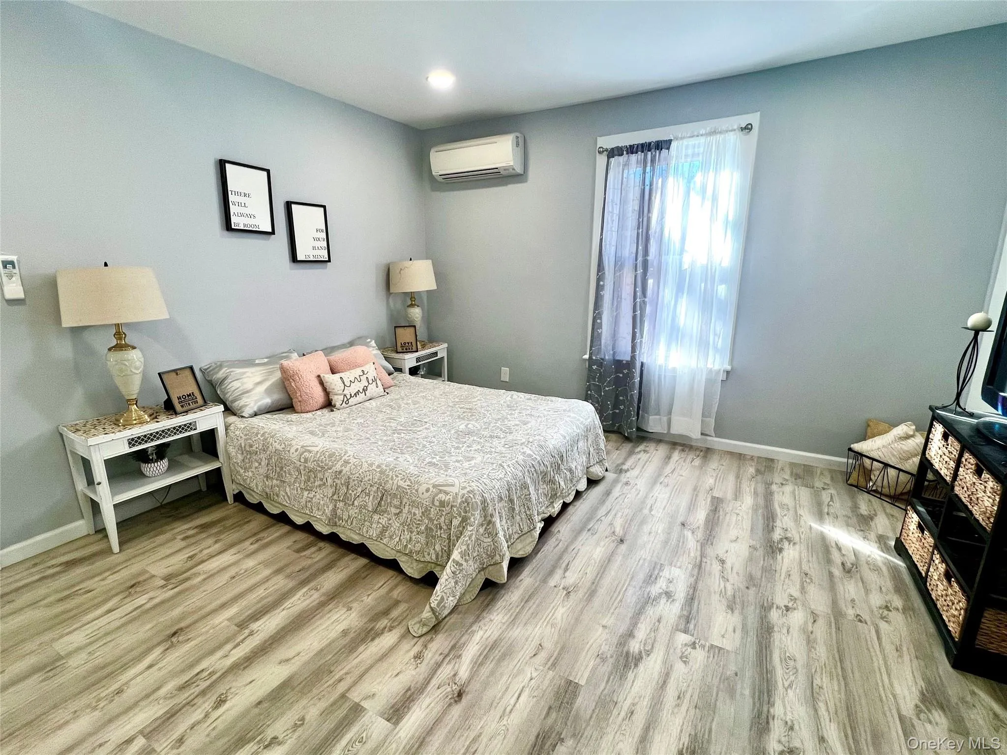 Bedroom with light wood finished floors and an AC wall unit Bedroom with light wood finished floors and an AC wall unit
