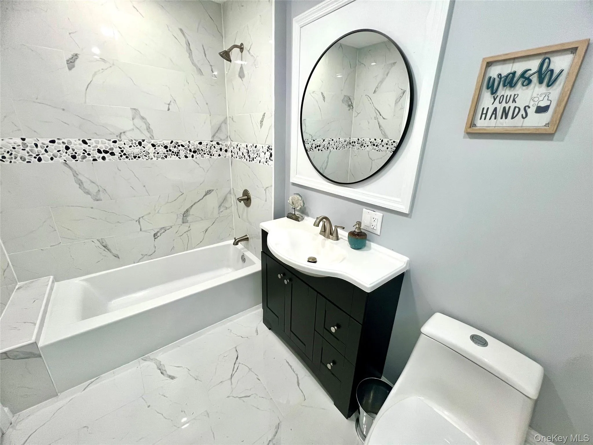 Bathroom with bathtub / shower combination, vanity, and light marble finish flooring Bathroom with bathtub / shower combination, vanity, and light marble finish flooring