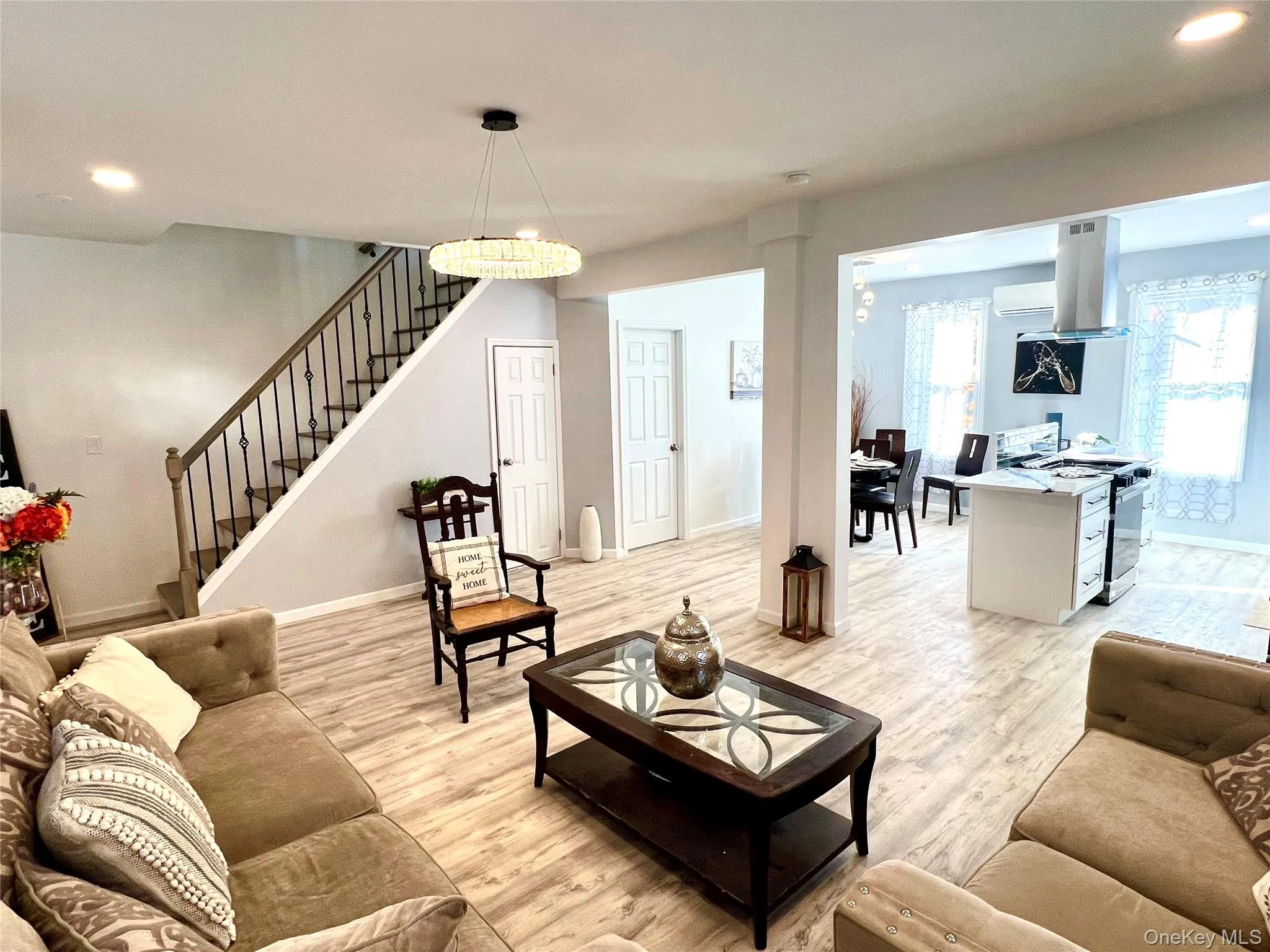 Living room featuring recessed lighting, light wood-style floors, stairs, a wall mounted AC, and a desk Living room featuring recessed lighting, light wood-style floors, stairs, a wall mounted AC, and a desk