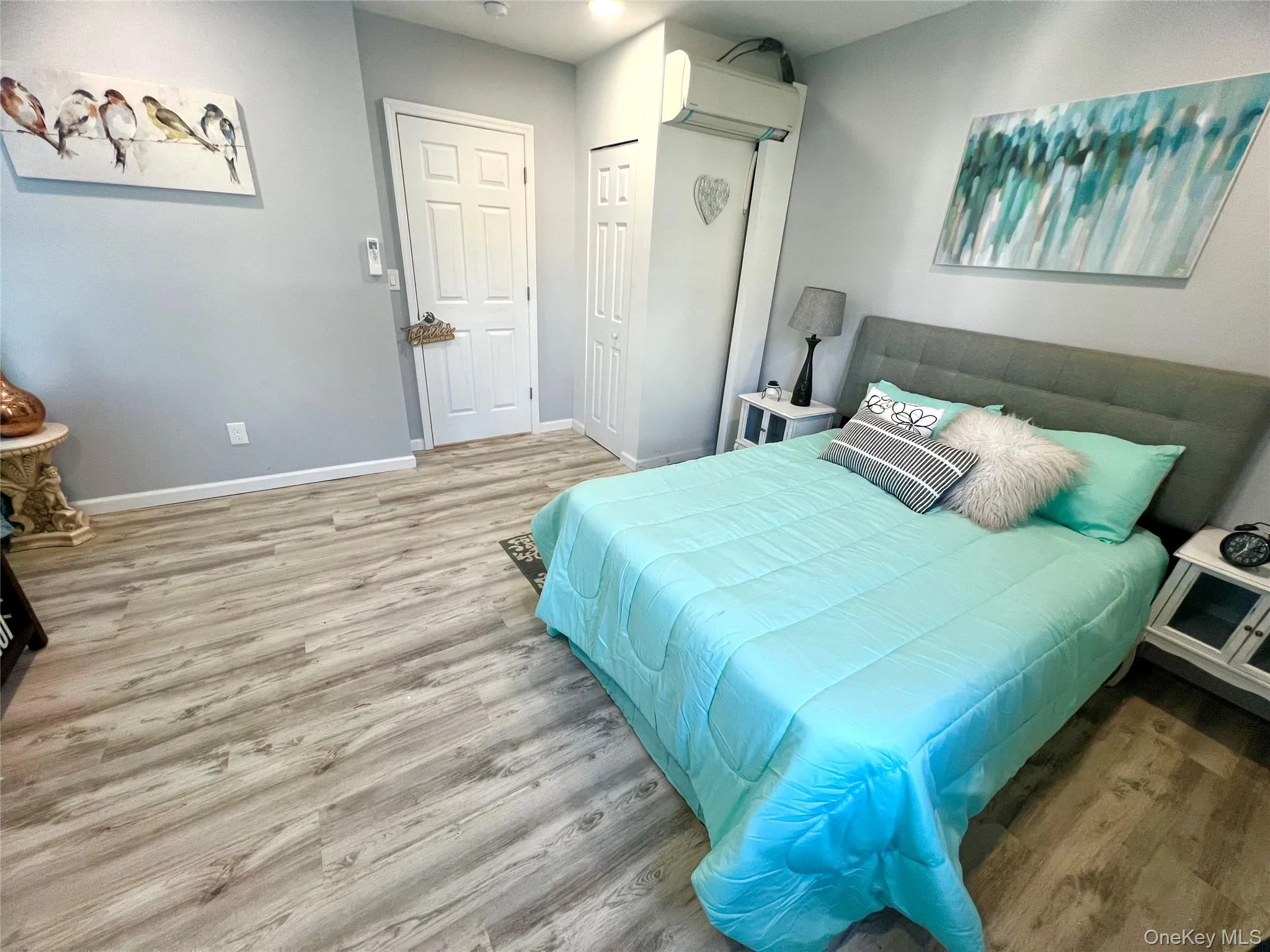 Bedroom with light wood-style flooring, an AC wall unit, and a closet Bedroom with light wood-style flooring, an AC wall unit, and a closet
