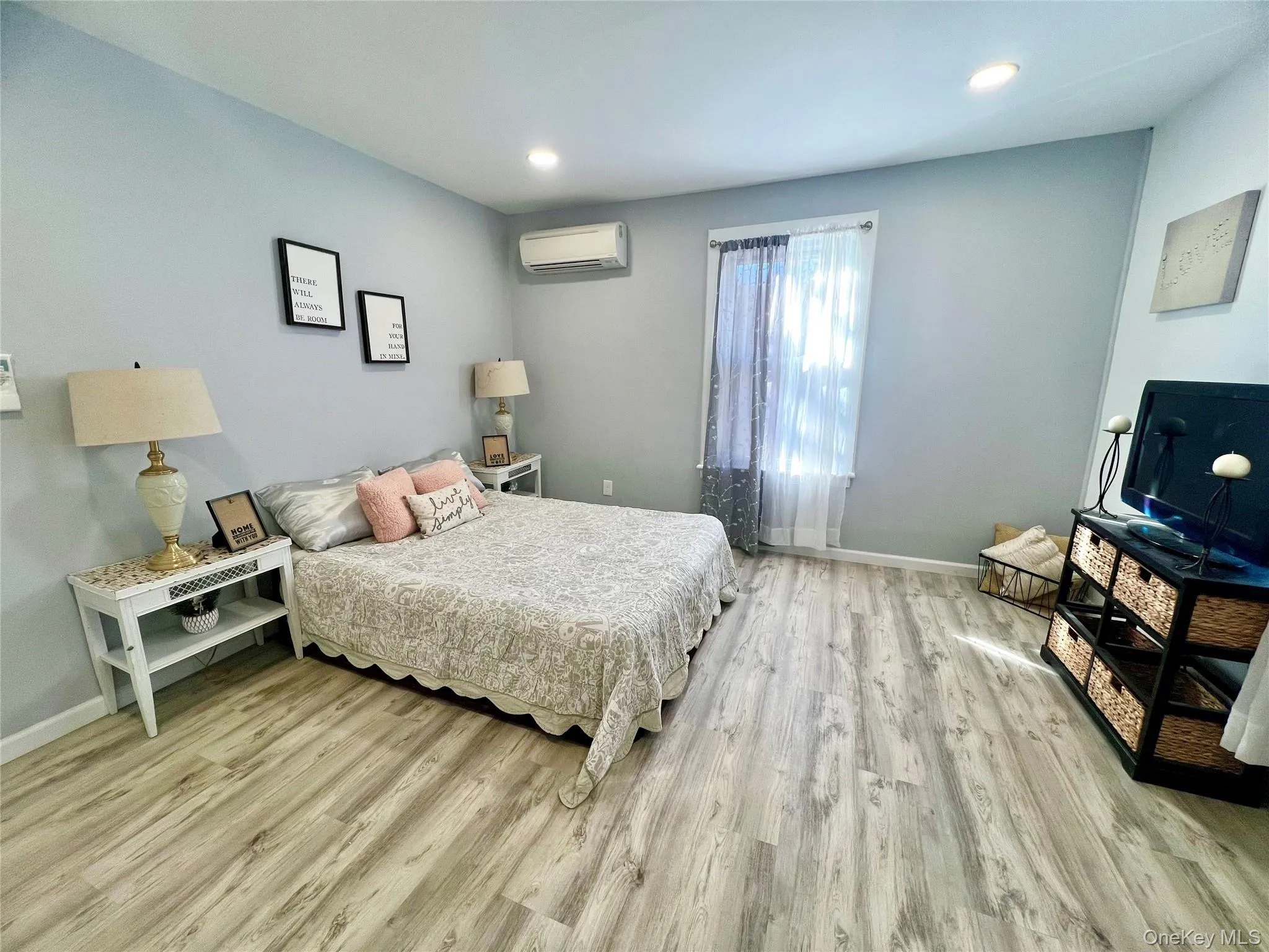 Bedroom featuring light wood-type flooring, recessed lighting, and a wall mounted air conditioner Bedroom featuring light wood-type flooring, recessed lighting, and a wall mounted air conditioner