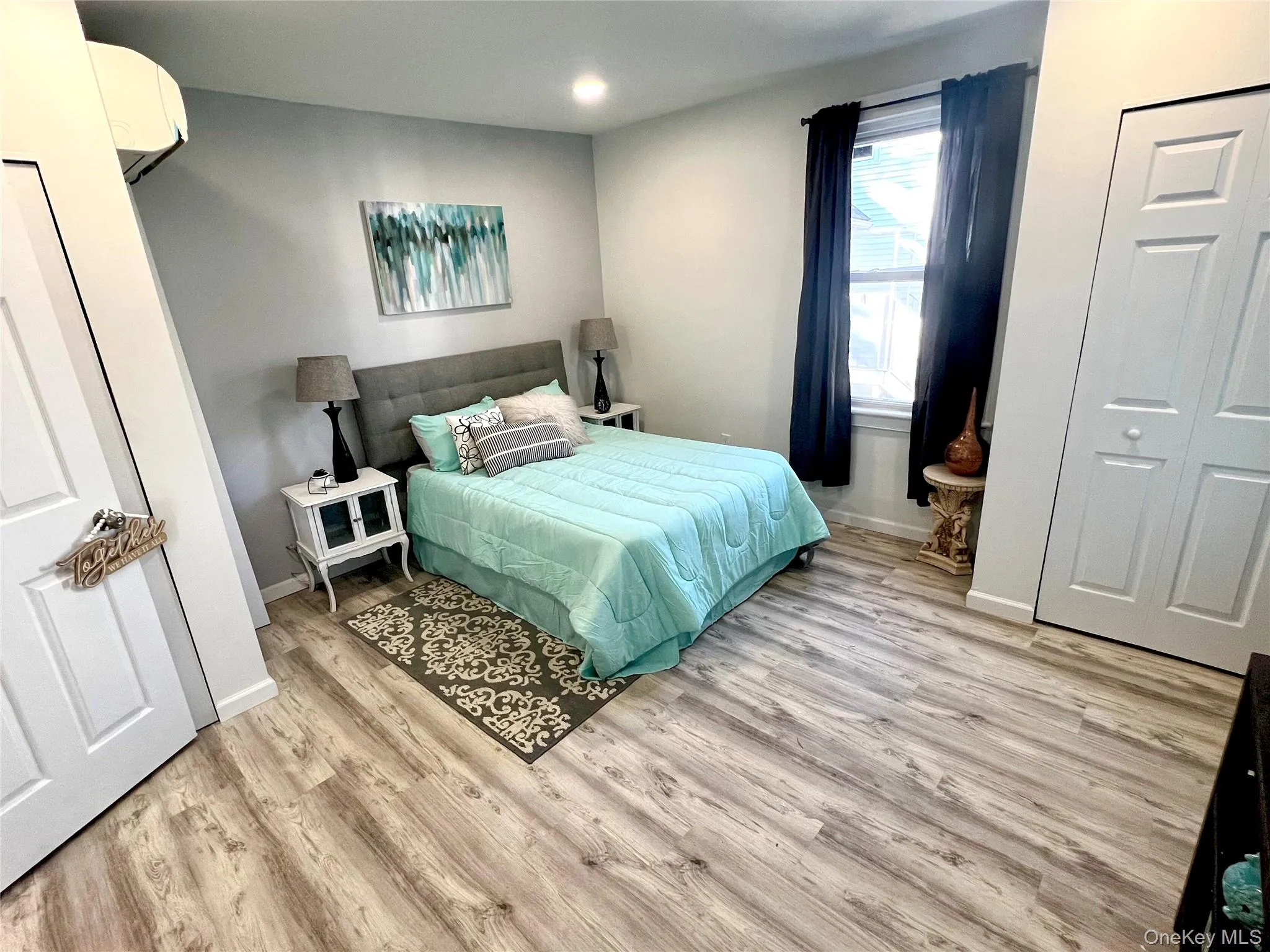 Bedroom with a closet, light wood-style flooring, an AC wall unit, and recessed lighting Bedroom with a closet, light wood-style flooring, an AC wall unit, and recessed lighting