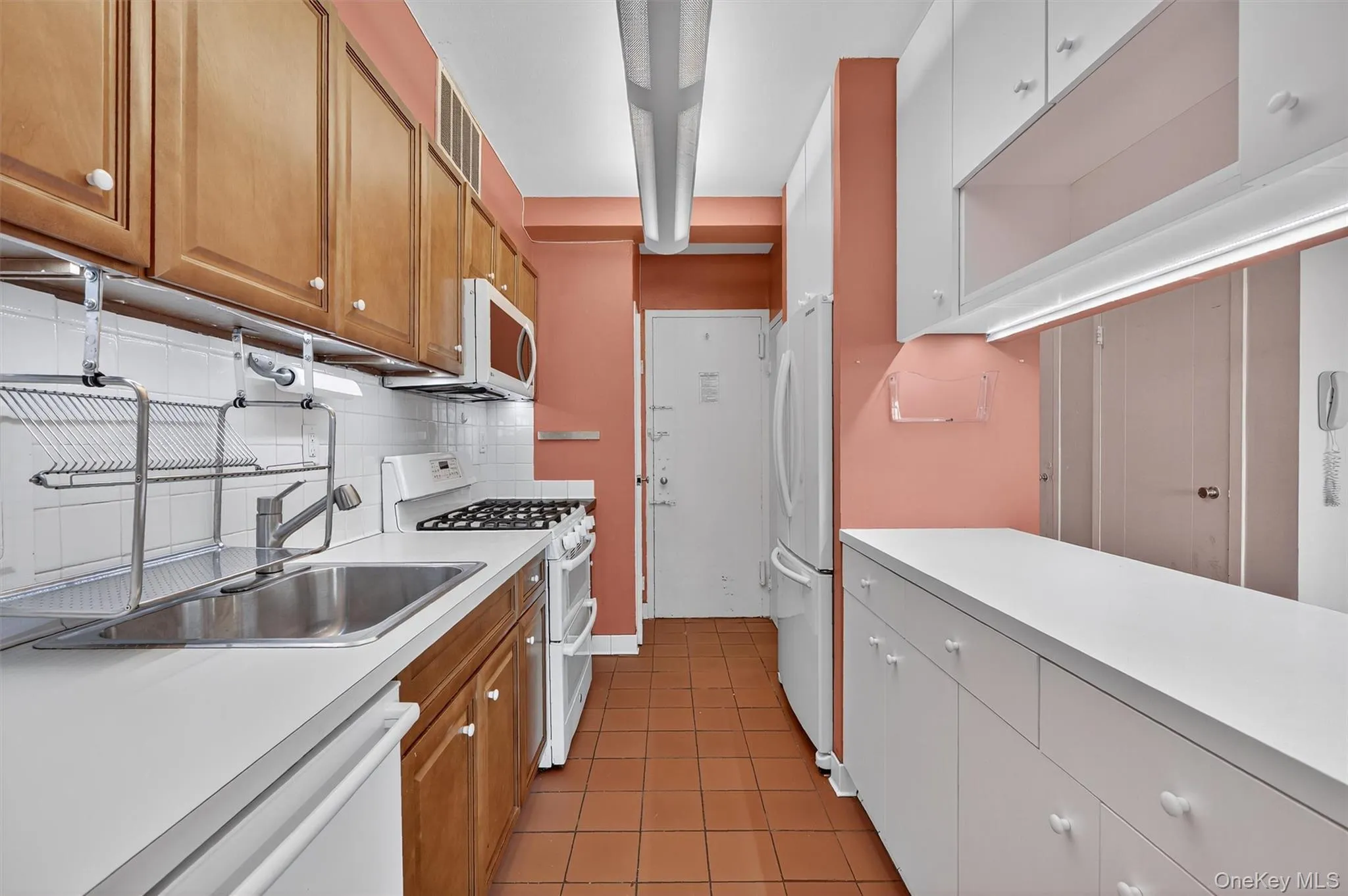 Kitchen with white appliances, light countertops, backsplash, and light tile patterned floors Kitchen with white appliances, light countertops, backsplash, and light tile patterned floors