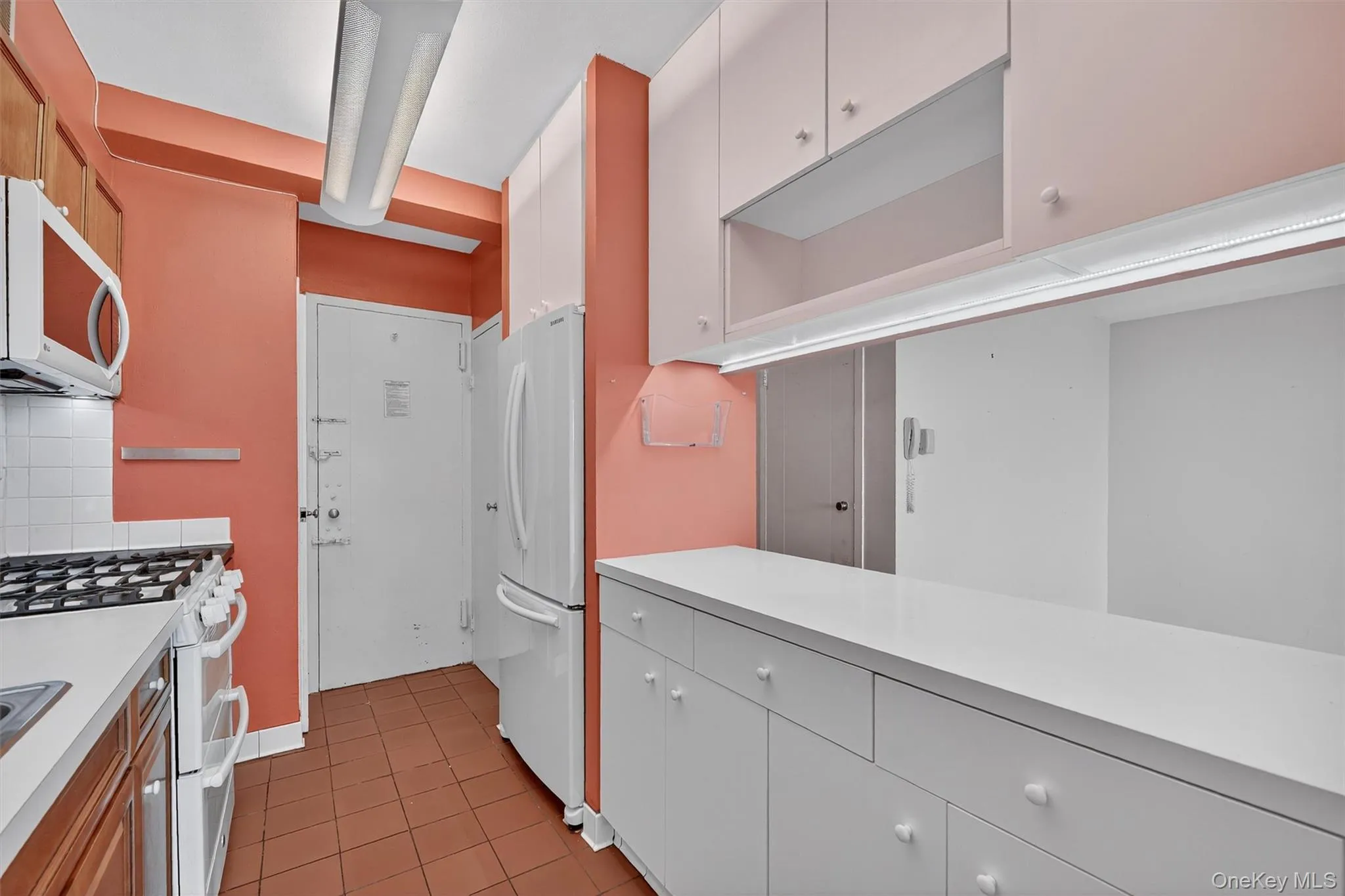 Kitchen featuring white appliances, light countertops, light tile patterned flooring, tasteful backsplash, and white cabinets Kitchen featuring white appliances, light countertops, light tile patterned flooring, tasteful backsplash, and white cabinets