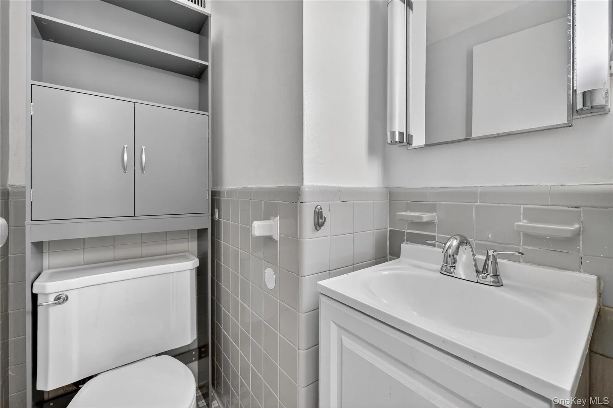 Bathroom with tile walls, vanity, and a wainscoted wall Bathroom with tile walls, vanity, and a wainscoted wall