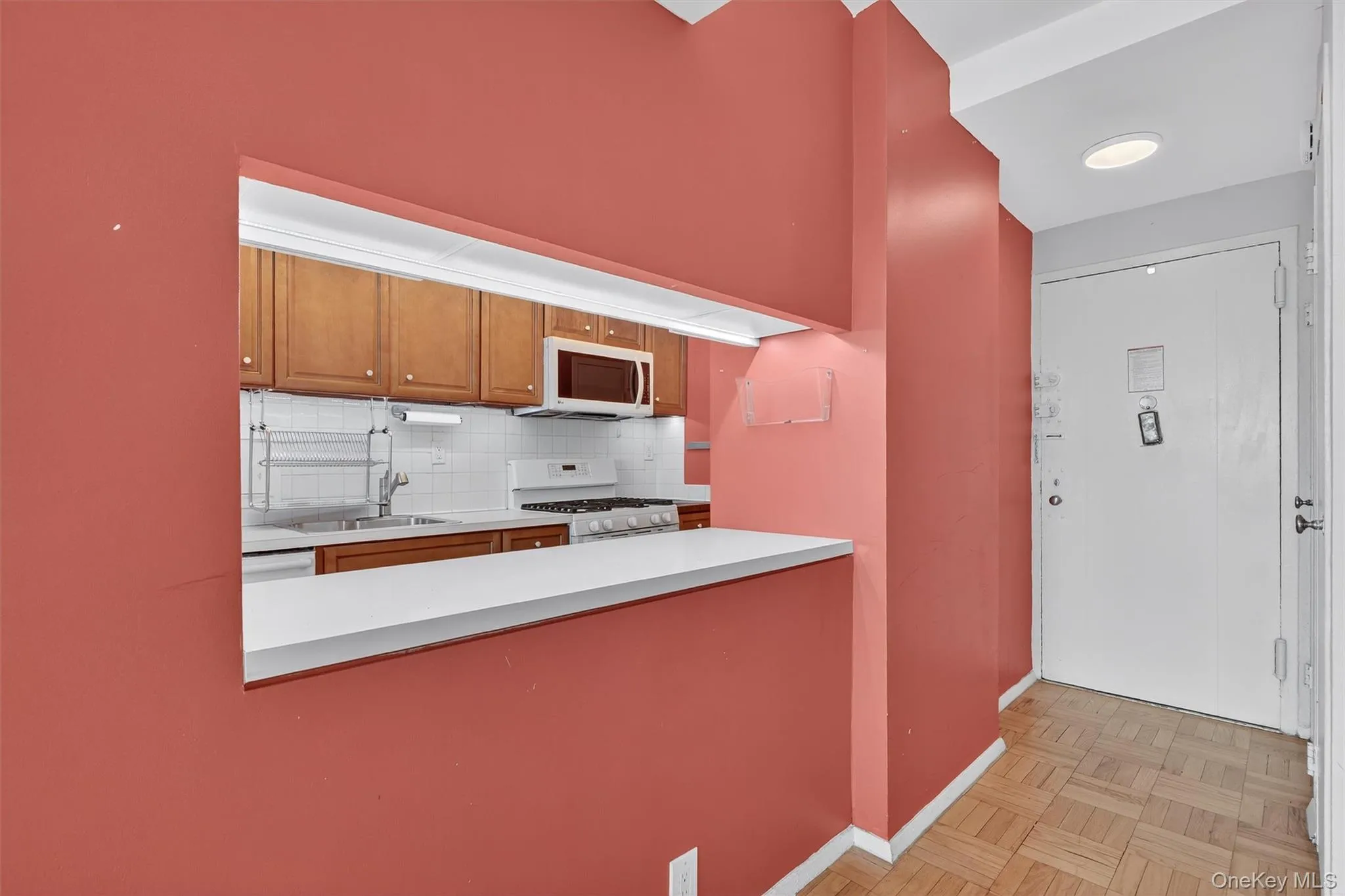 Kitchen with white appliances, backsplash, brown cabinets, light countertops, and a peninsula Kitchen with white appliances, backsplash, brown cabinets, light countertops, and a peninsula