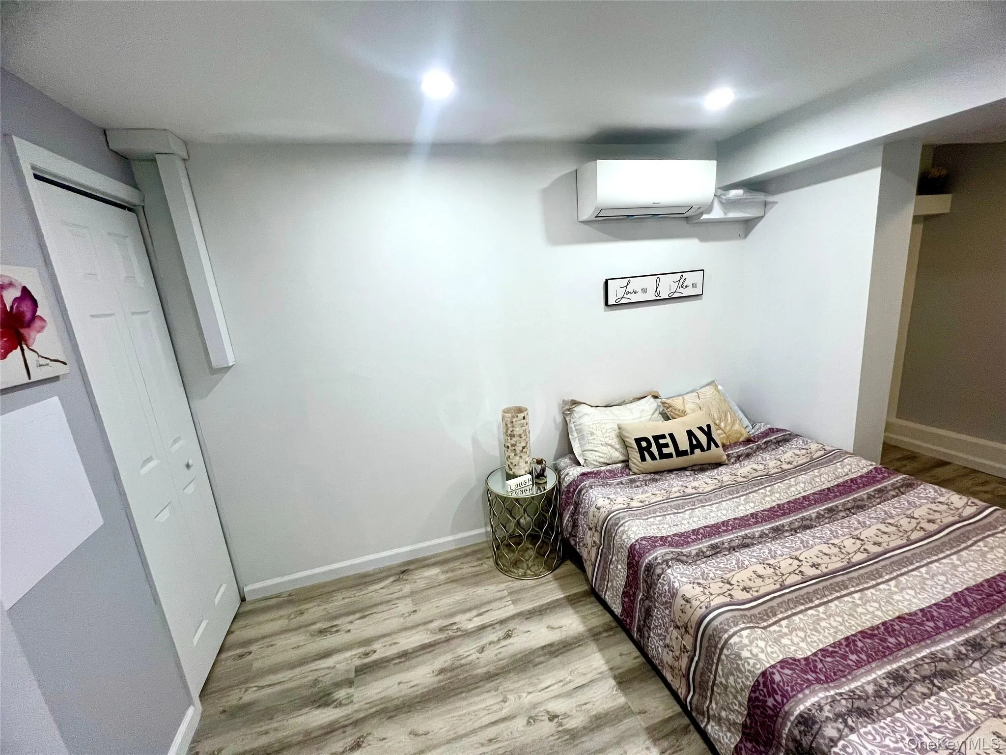 Bedroom featuring light wood finished floors and an AC wall unit Bedroom featuring light wood finished floors and an AC wall unit