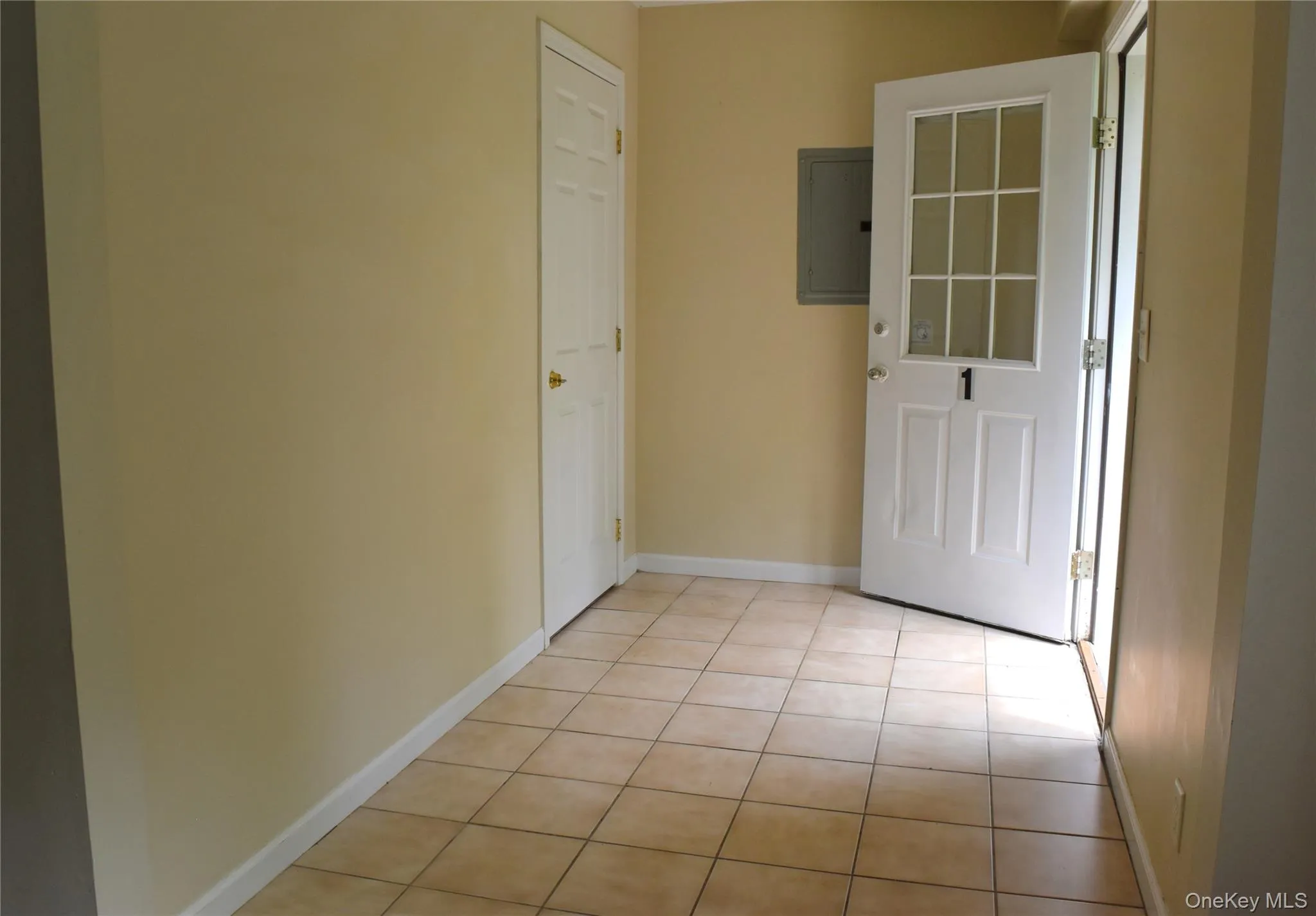 Unfurnished room with electric panel, light tile patterned flooring, and baseboards Unfurnished room with electric panel, light tile patterned flooring, and baseboards