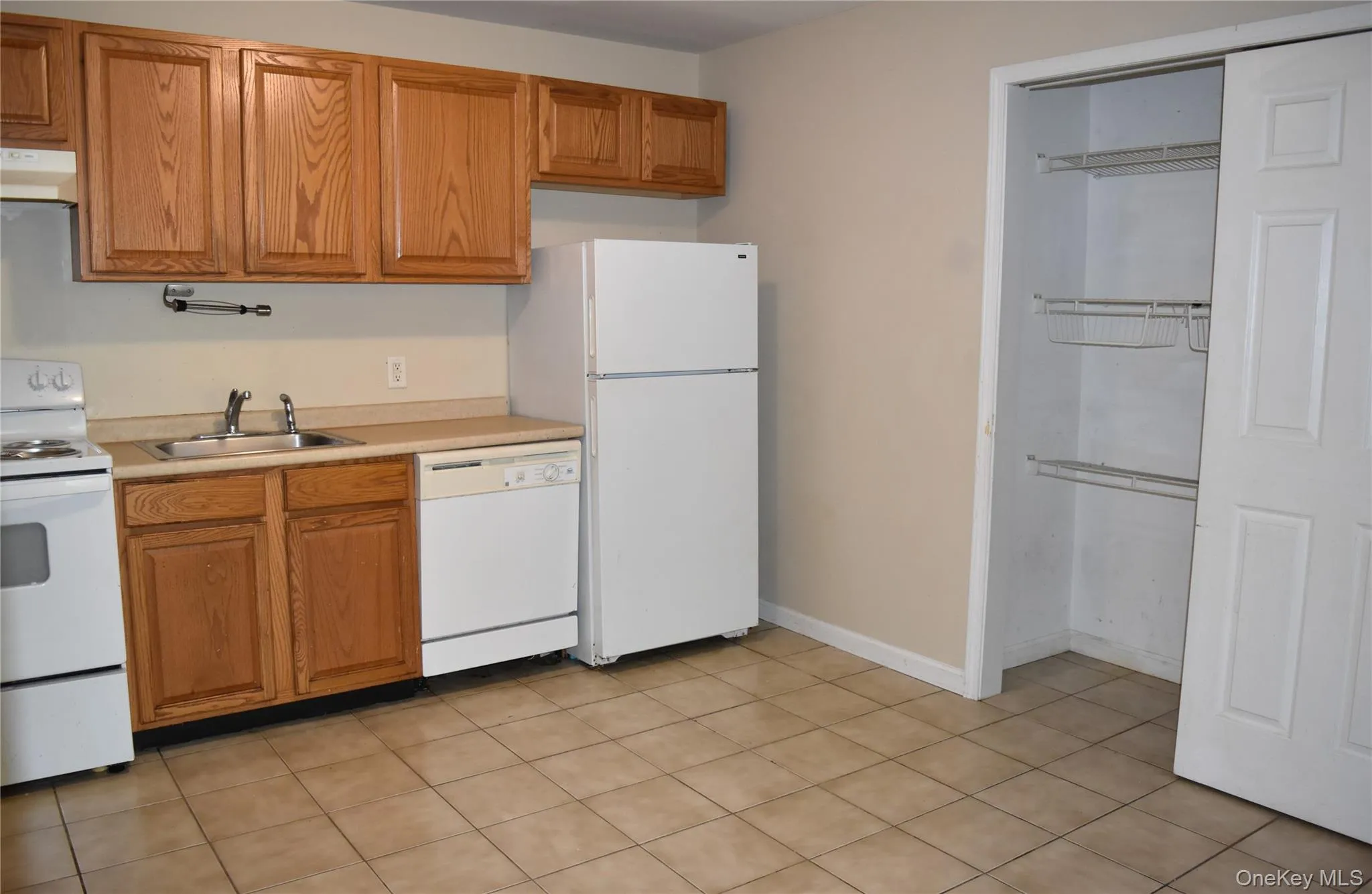 Kitchen featuring white appliances, under cabinet range hood, a sink, light countertops, and brown cabinets Kitchen featuring white appliances, under cabinet range hood, a sink, light countertops, and brown cabinets