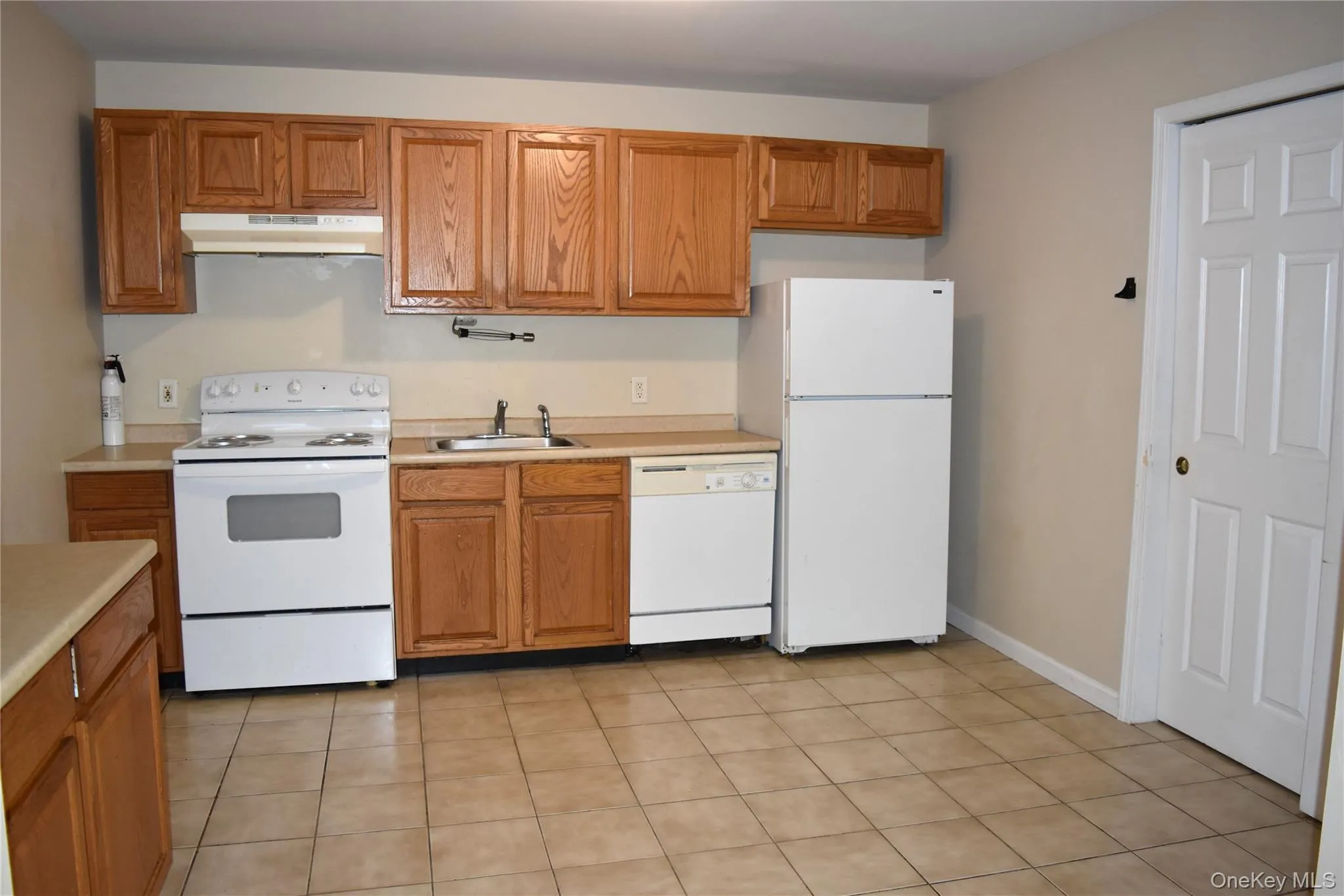 Kitchen with white appliances, under cabinet range hood, light countertops, and a sink Kitchen with white appliances, under cabinet range hood, light countertops, and a sink