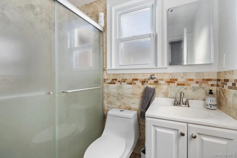 Bathroom featuring vanity, a stall shower, and tile walls Bathroom featuring vanity, a stall shower, and tile walls