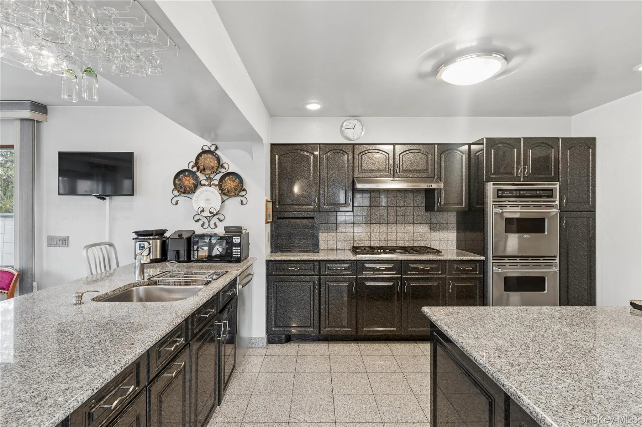 Kitchen featuring light stone countertops, dark finish cabinets, stainless steel appliances, granite floors, and recessed lighting Kitchen featuring light stone countertops, dark finish cabinets, stainless steel appliances, granite floors, and recessed lighting