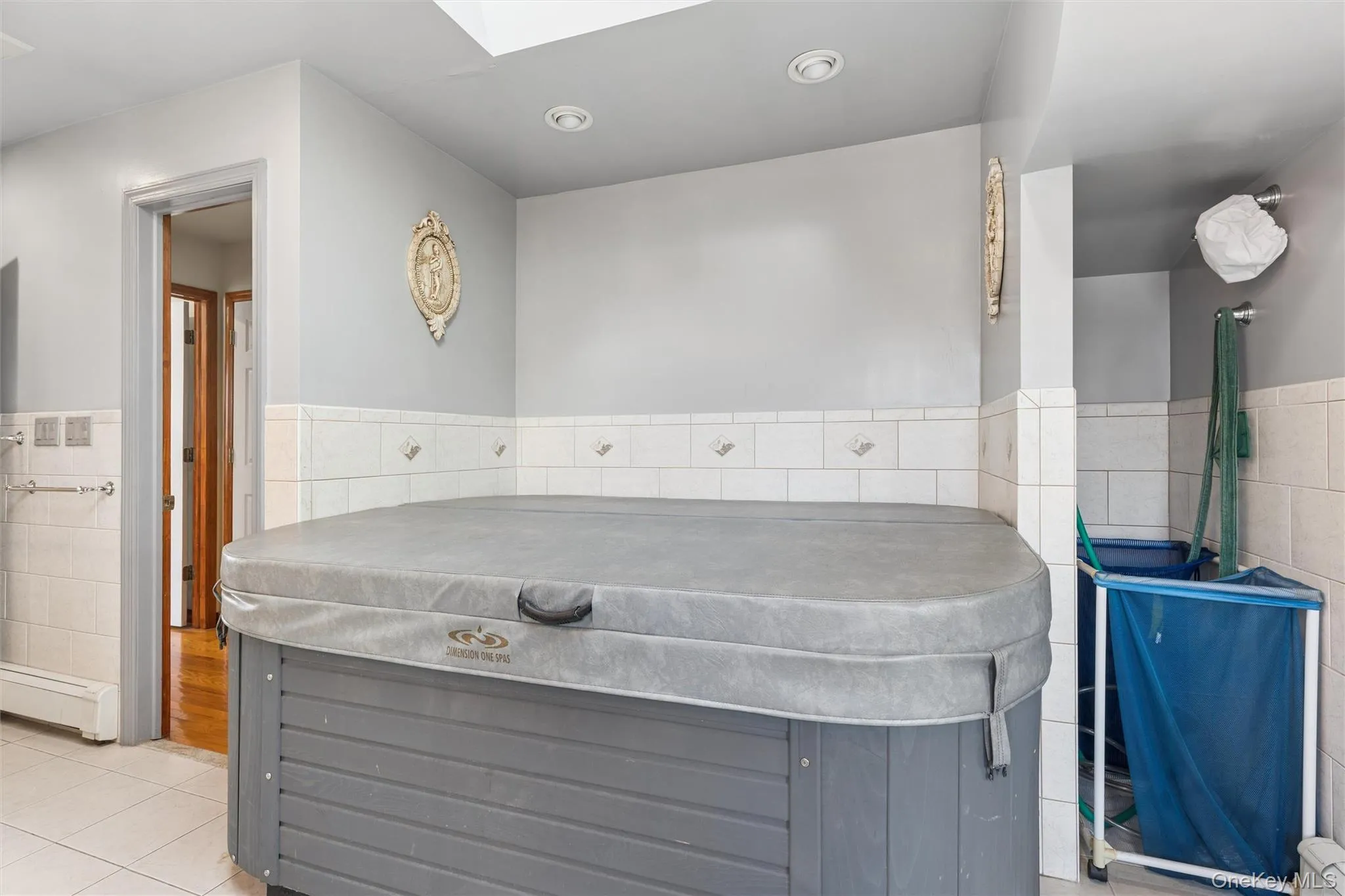 Master Bathroom Suite Detailed view of a hot tub, tile walls, a wainscoted wall, a skylight, and a baseboard radiator Master Bathroom Suite Detailed view of a hot tub, tile walls, a wainscoted wall, a skylight, and a baseboard radiator