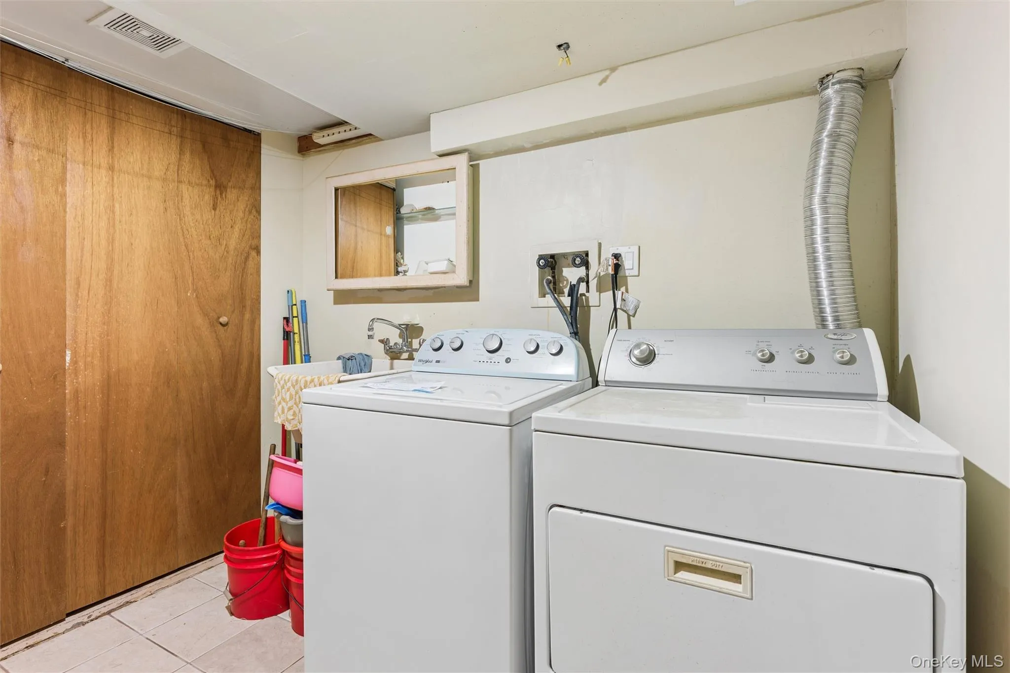 Laundry room with independent washer and dryer and light tile patterned flooring Laundry room with independent washer and dryer and light tile patterned flooring